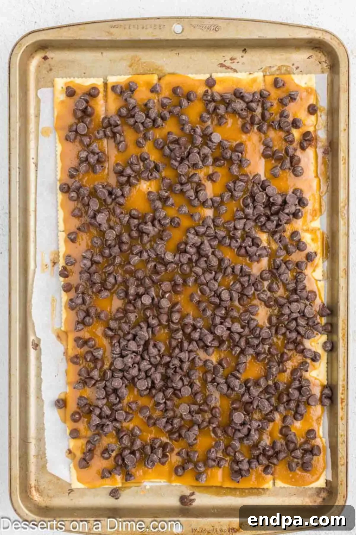 Sweet and Salty Toffee Bark 7 Chocolate chips scattered generously over the hot toffee-covered crackers, beginning to melt from the residual heat.