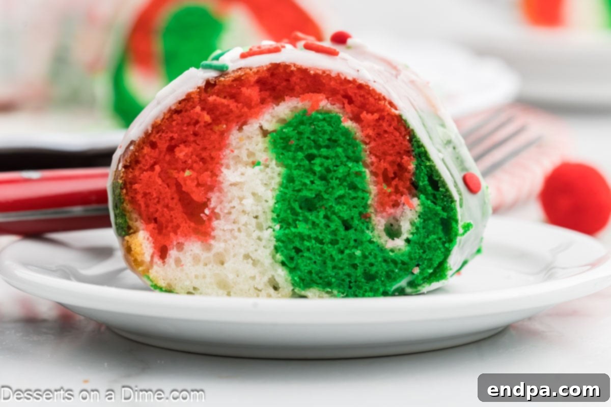 Slice of Christmas bundt cake on a white plate, showcasing red, green, and white swirls.
