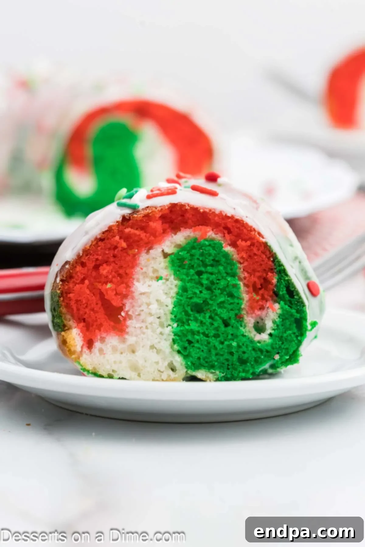 Christmas Bundt Cake with red, green, and white swirls, beautifully sliced on a white plate.