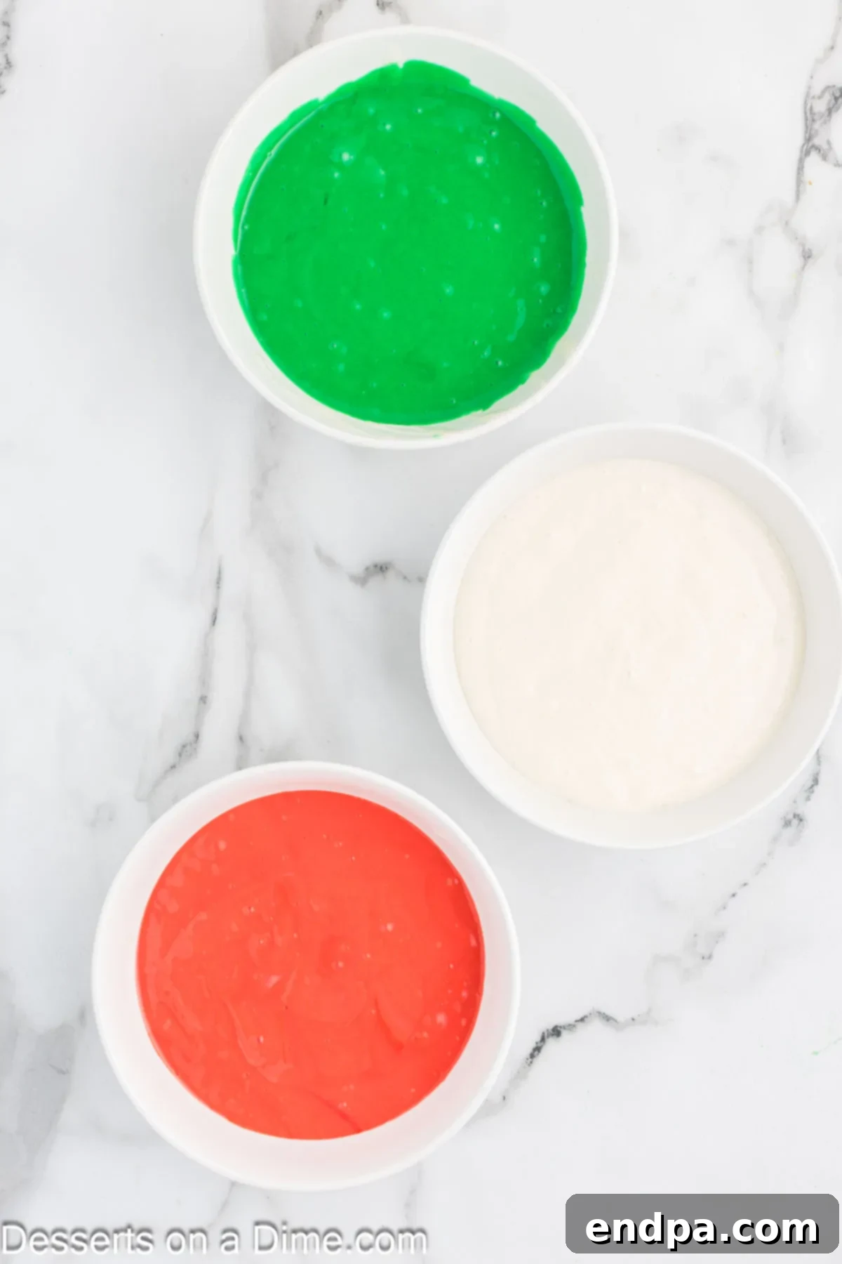 Mixing bowls with cake batter separated into white, red, and green colors.