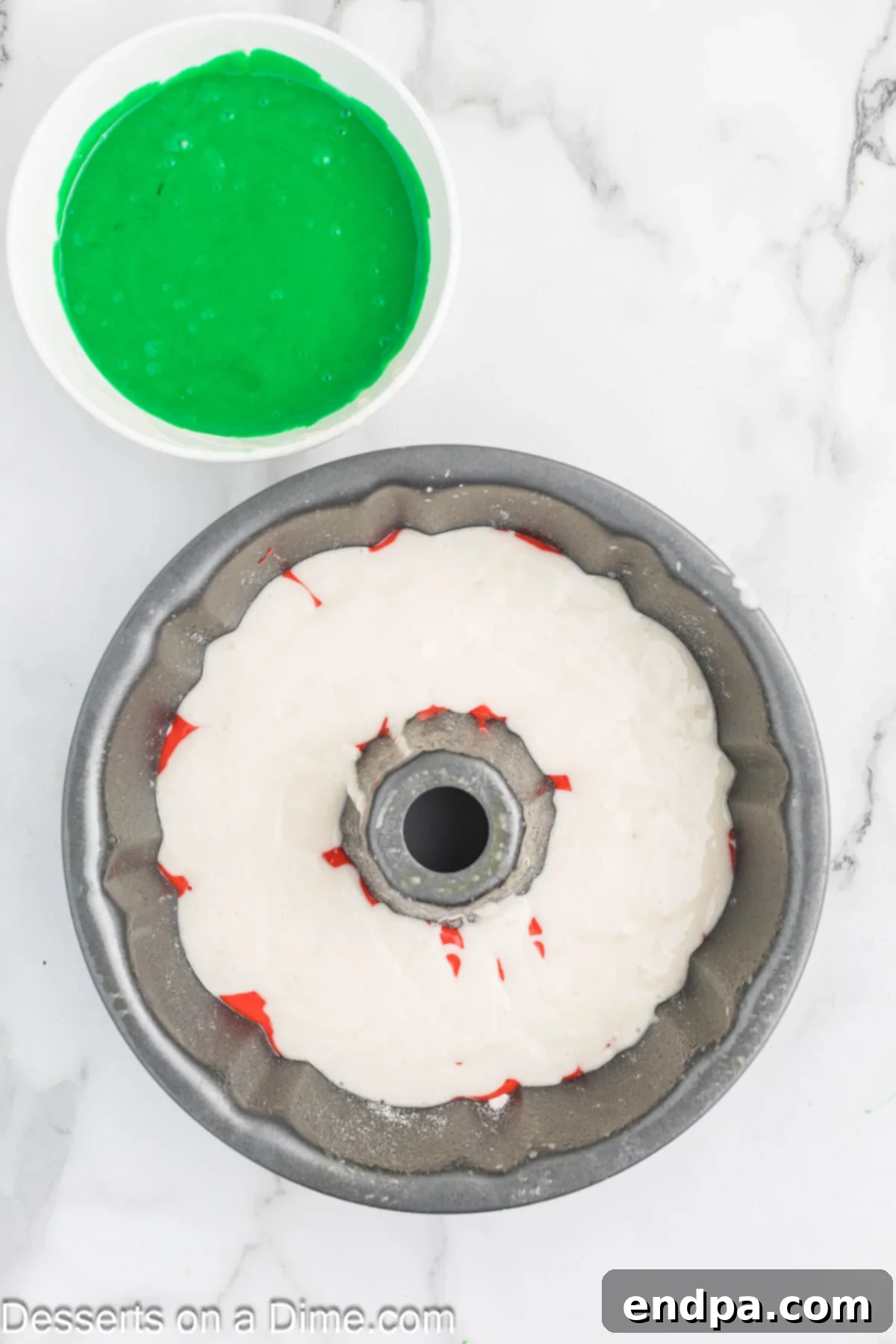 Uncolored white cake batter spread evenly into the bottom of a Bundt cake pan.