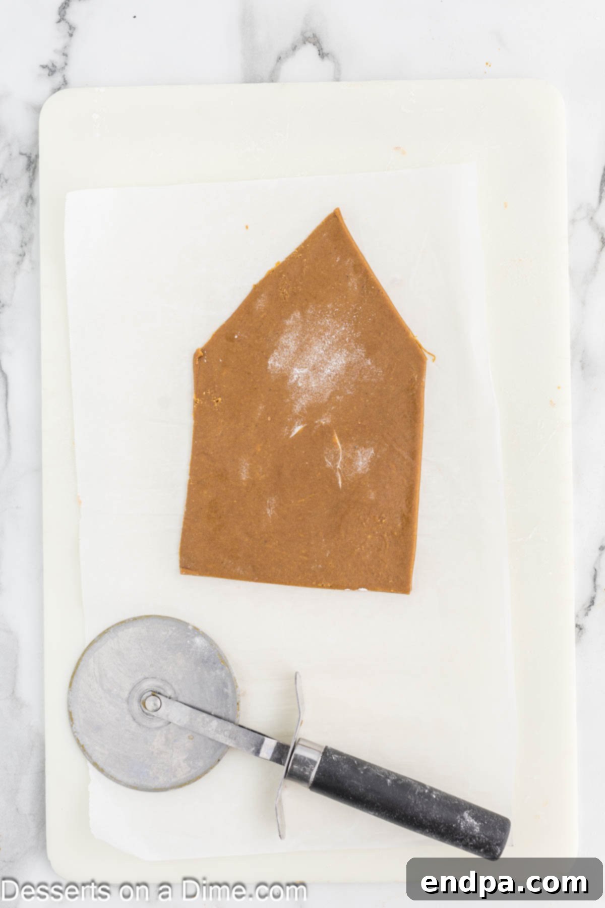 Spiced Sugar Sanctuary 7 Gingerbread dough carefully cut into various house shapes, such as walls and roof pieces, using a pizza cutter on parchment paper.
