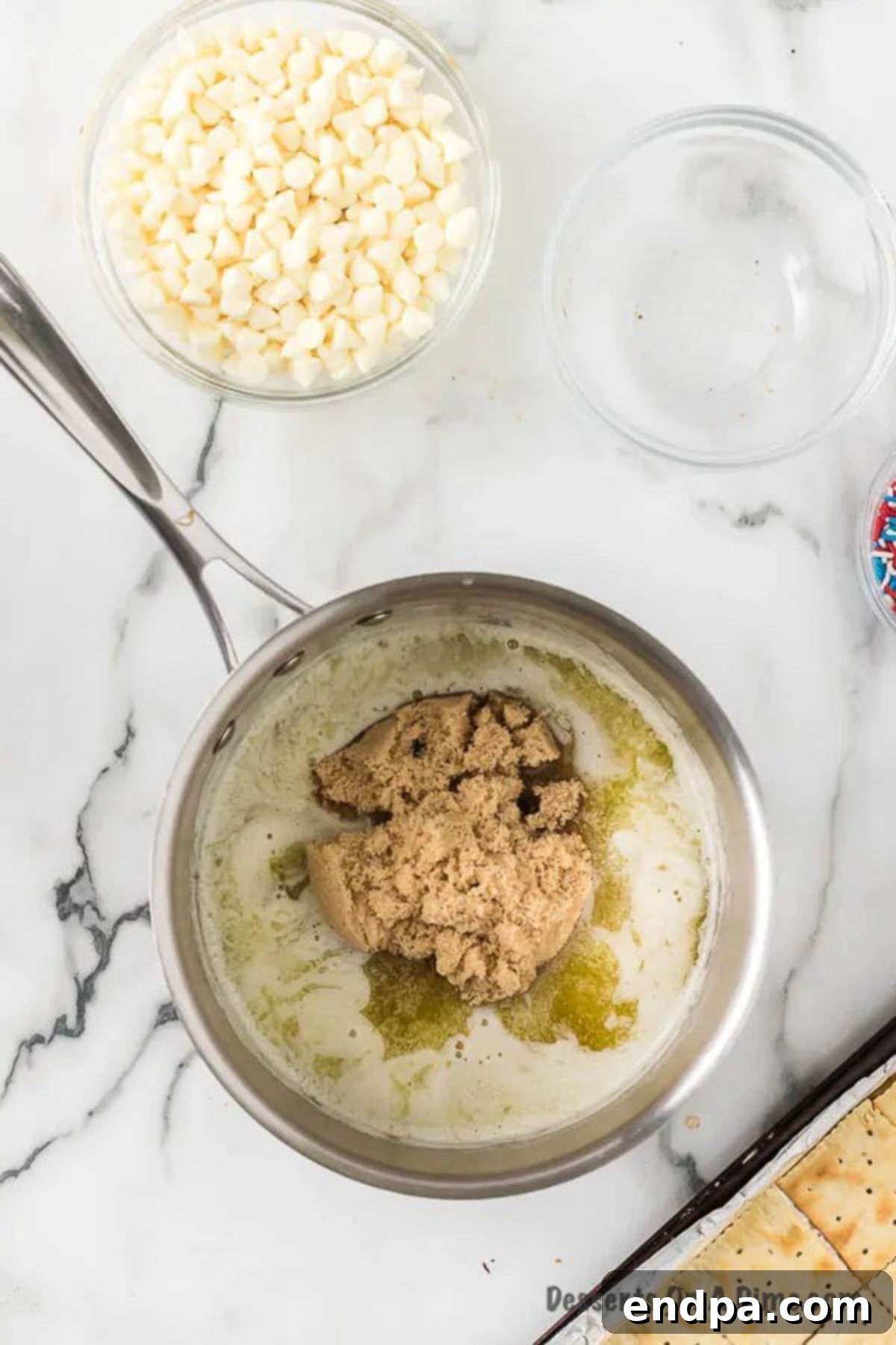 A close-up of butter and rich brown sugar melting together in a saucepan over gentle heat, forming the luscious toffee mixture for the crackers.
