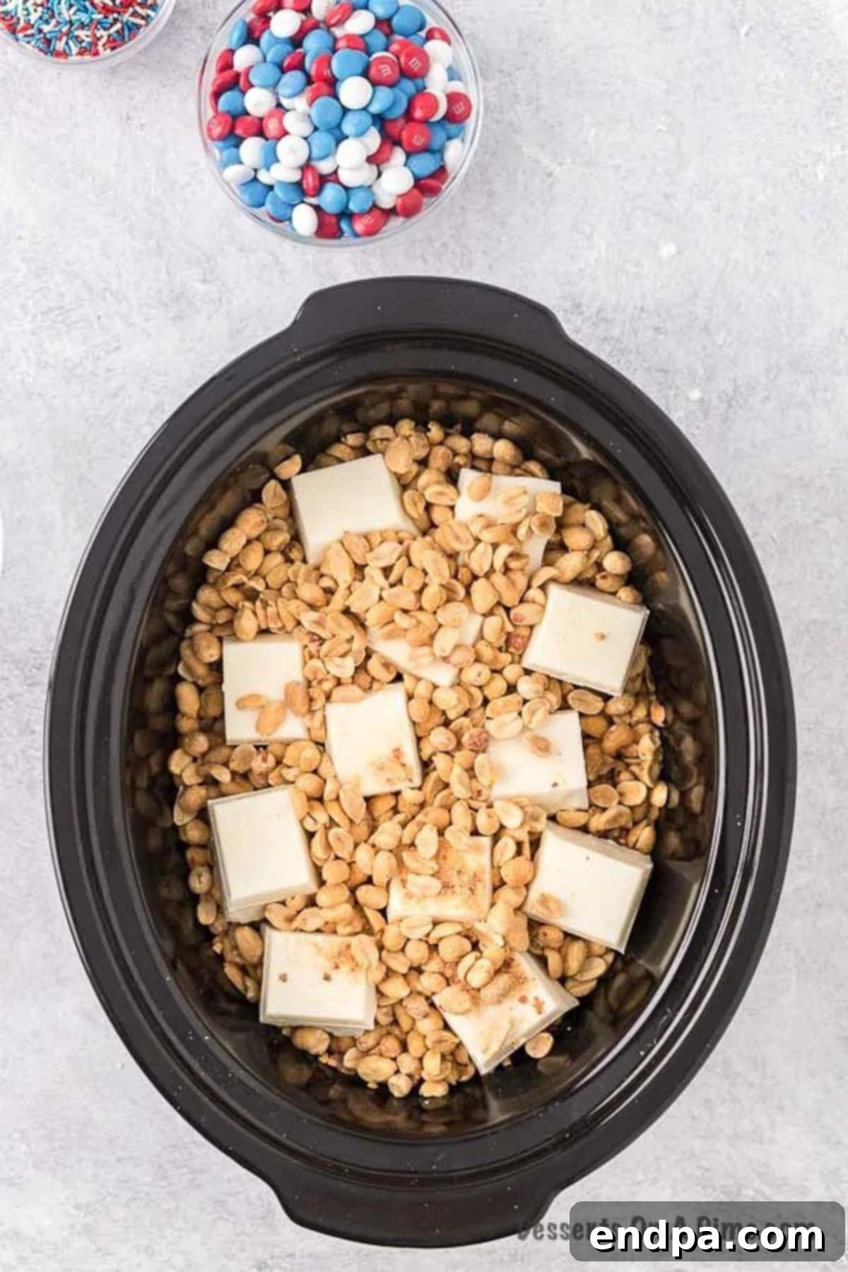 Crock Pot filled with layers of peanuts and almond bark, ready to melt.