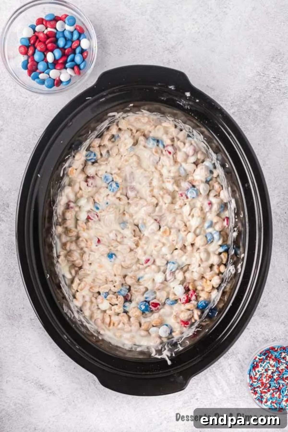 Half of the M&M's folded into the melted chocolate peanut mixture in the slow cooker.