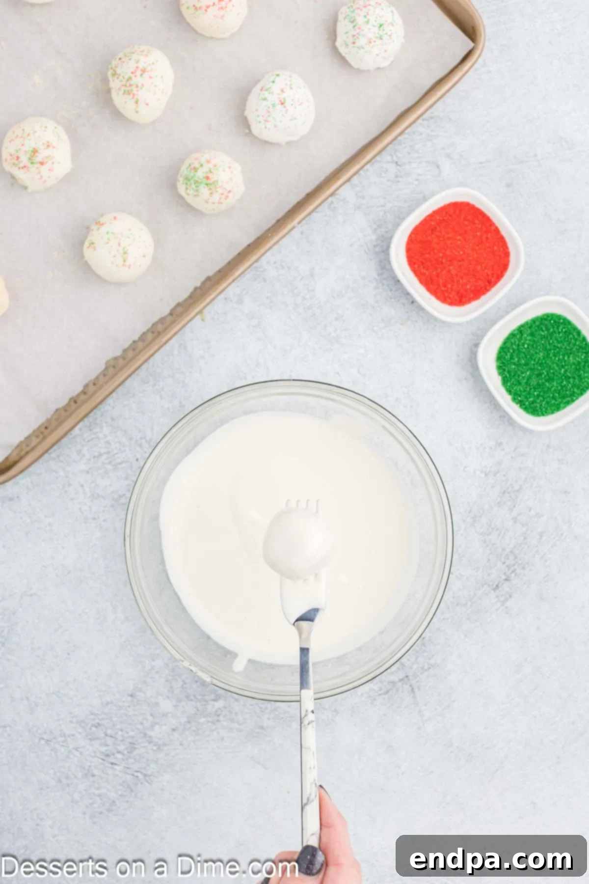 Cake balls being dipped in bowl.
