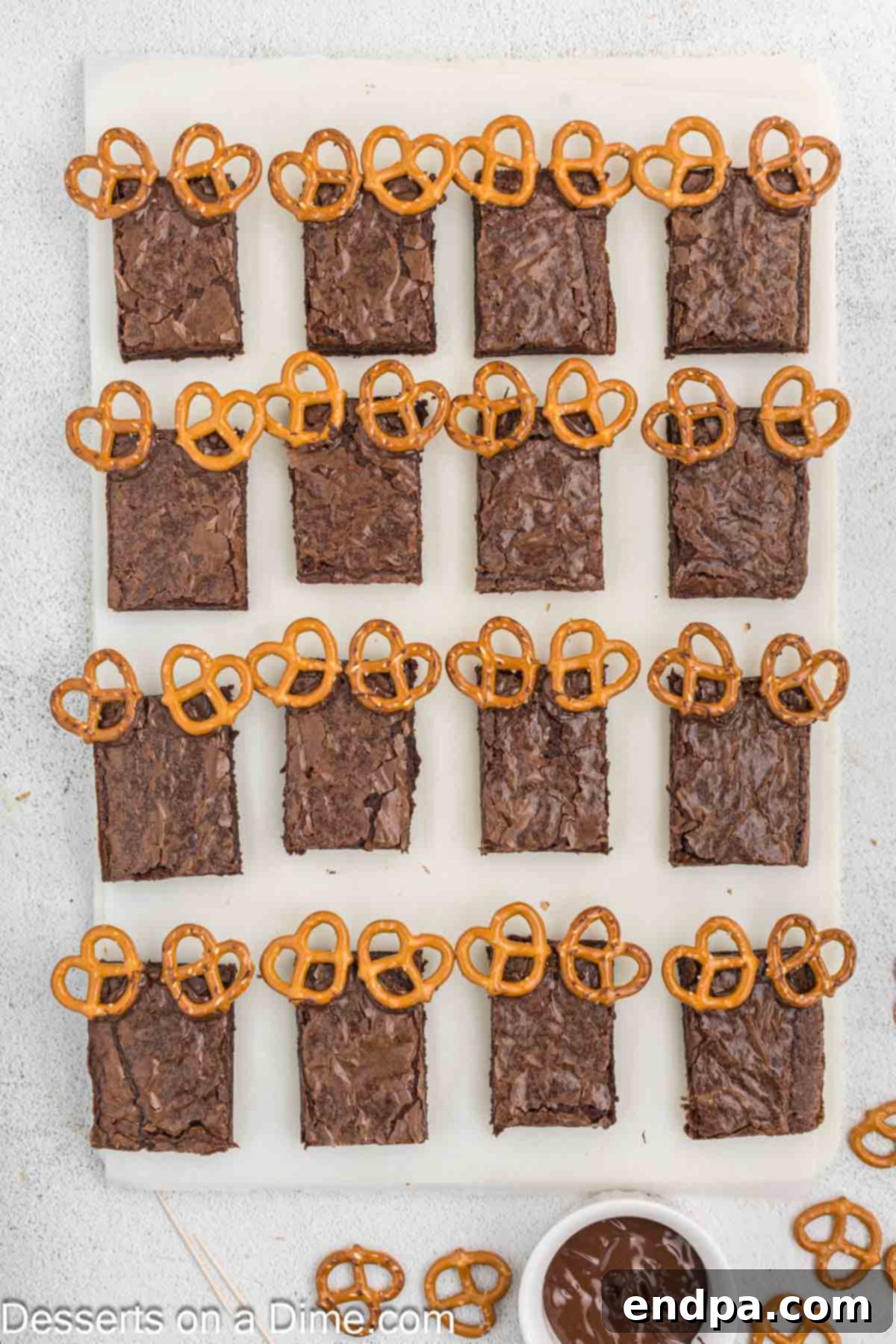 Christmas Antler Brownies 5 Close-up of brownie slices, each adorned with two mini pretzel twists carefully placed at the top corners to form adorable reindeer antlers, secured with melted chocolate.