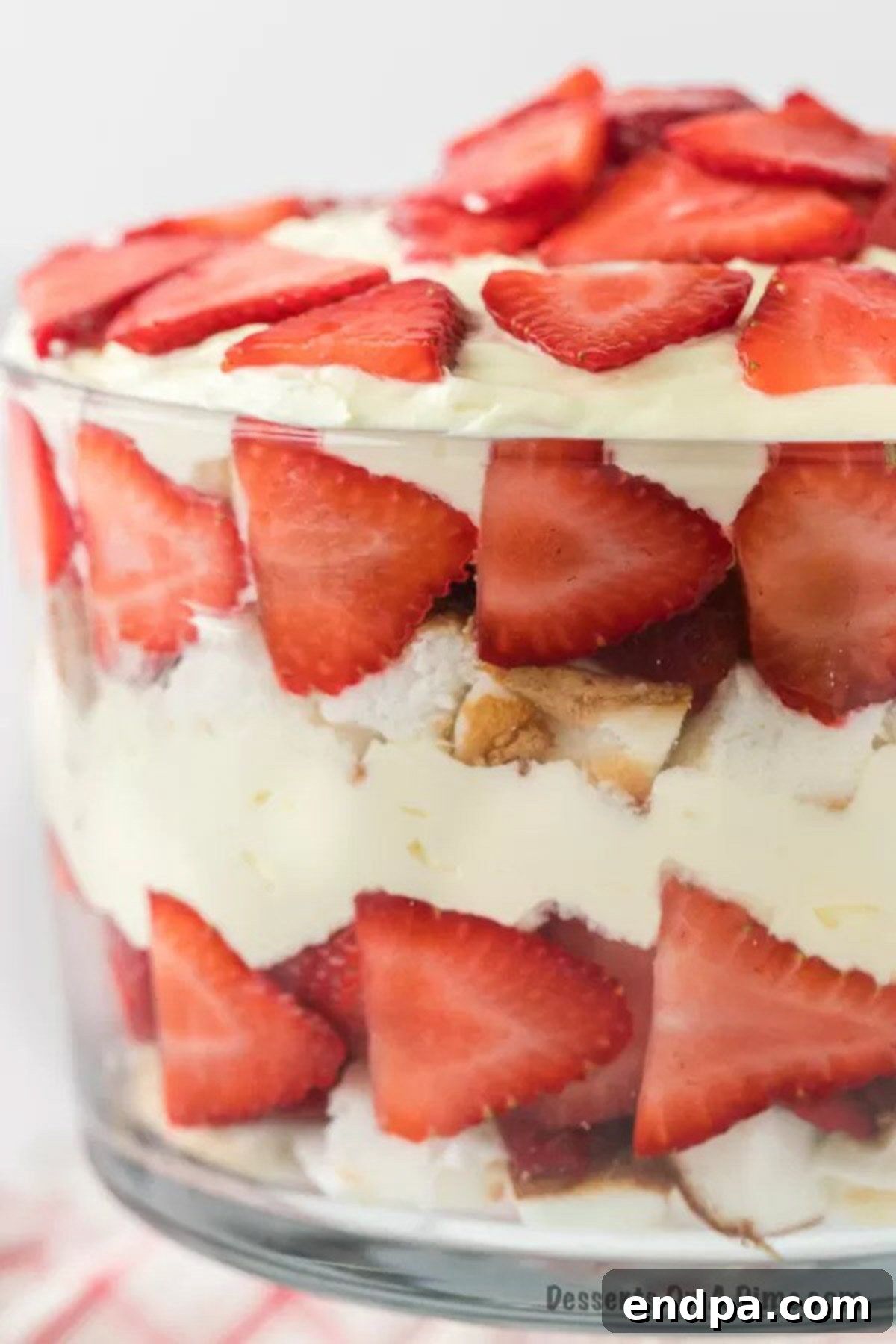 Close up of trifle dish with layers of cake, filling and fruit. 