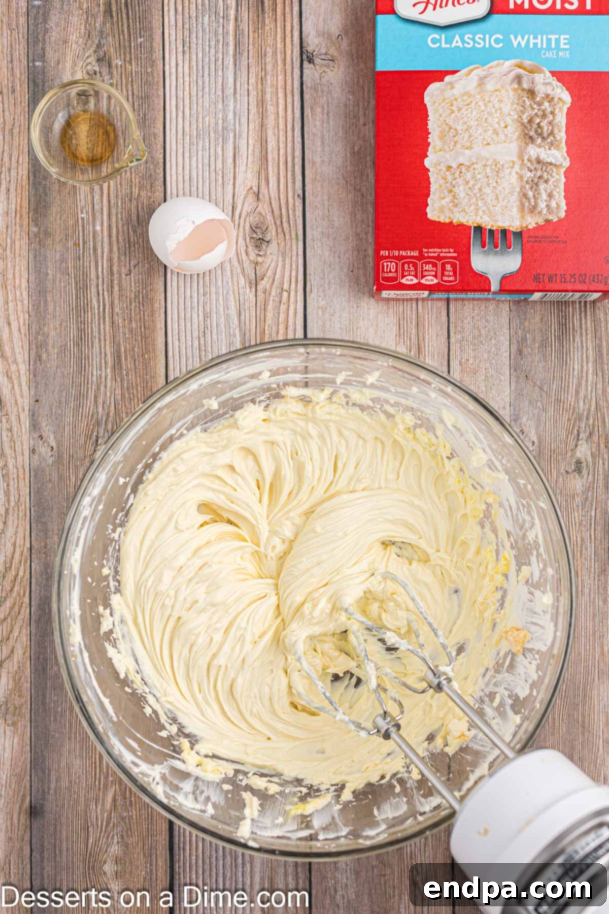 Mixing egg and vanilla extract into the creamed butter and cream cheese mixture.