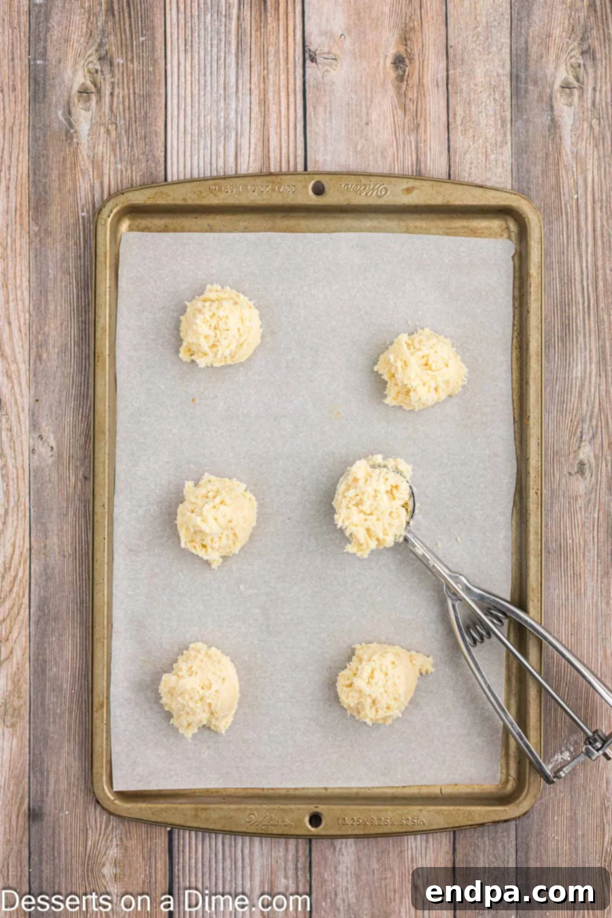 Scooping uniform balls of cookie dough onto a parchment-lined baking sheet.