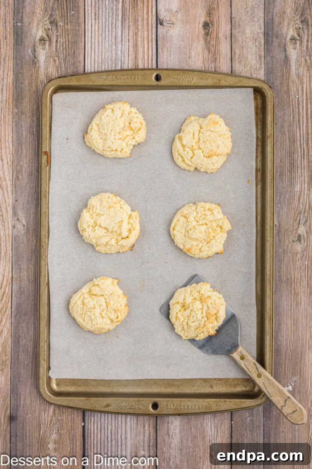 Freshly baked cream cheese cake mix cookies on a baking sheet, golden around the edges.