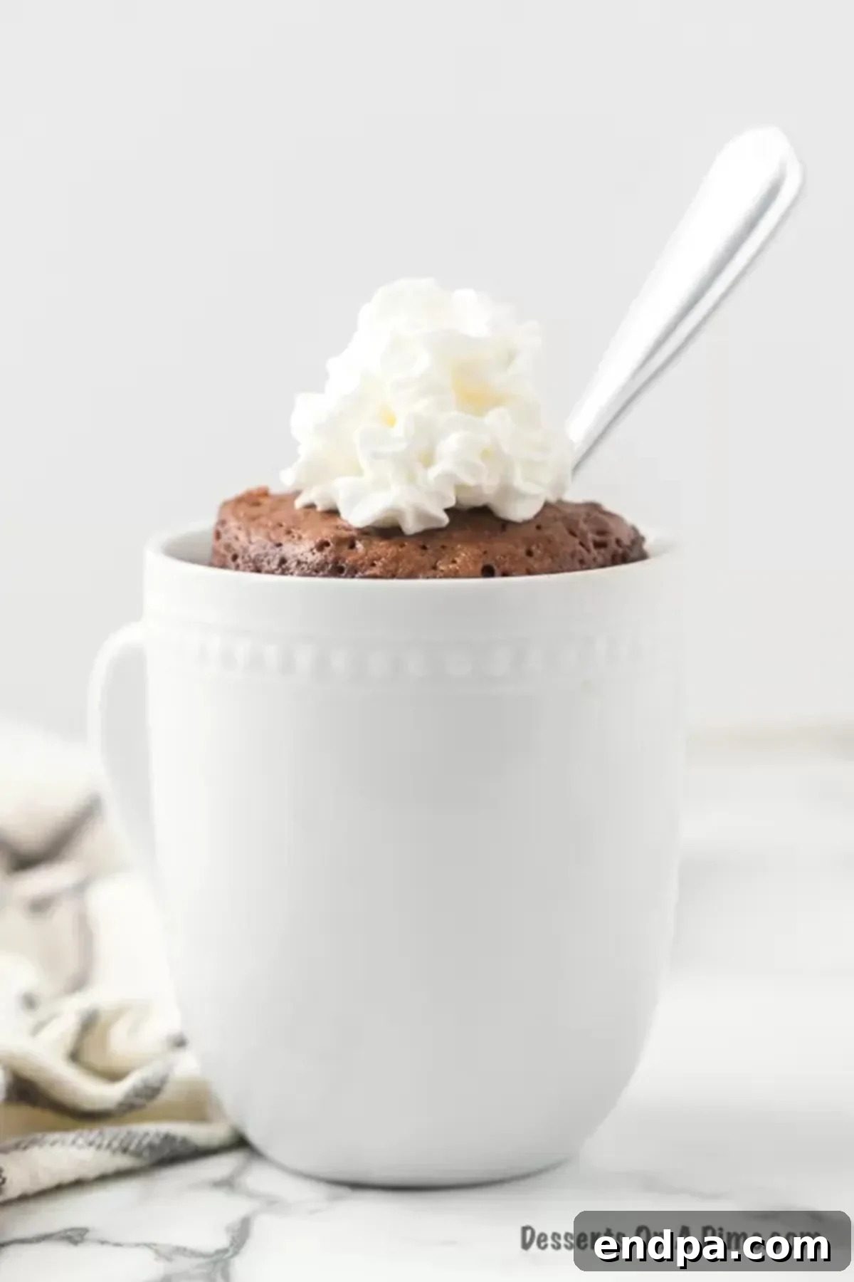 Nutella mug cake topped with whipped cream and a spoon