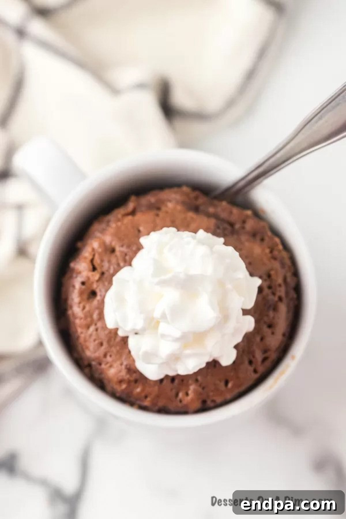 Finished Nutella Mug Cake with a spoon and whipped cream on top, ready to eat