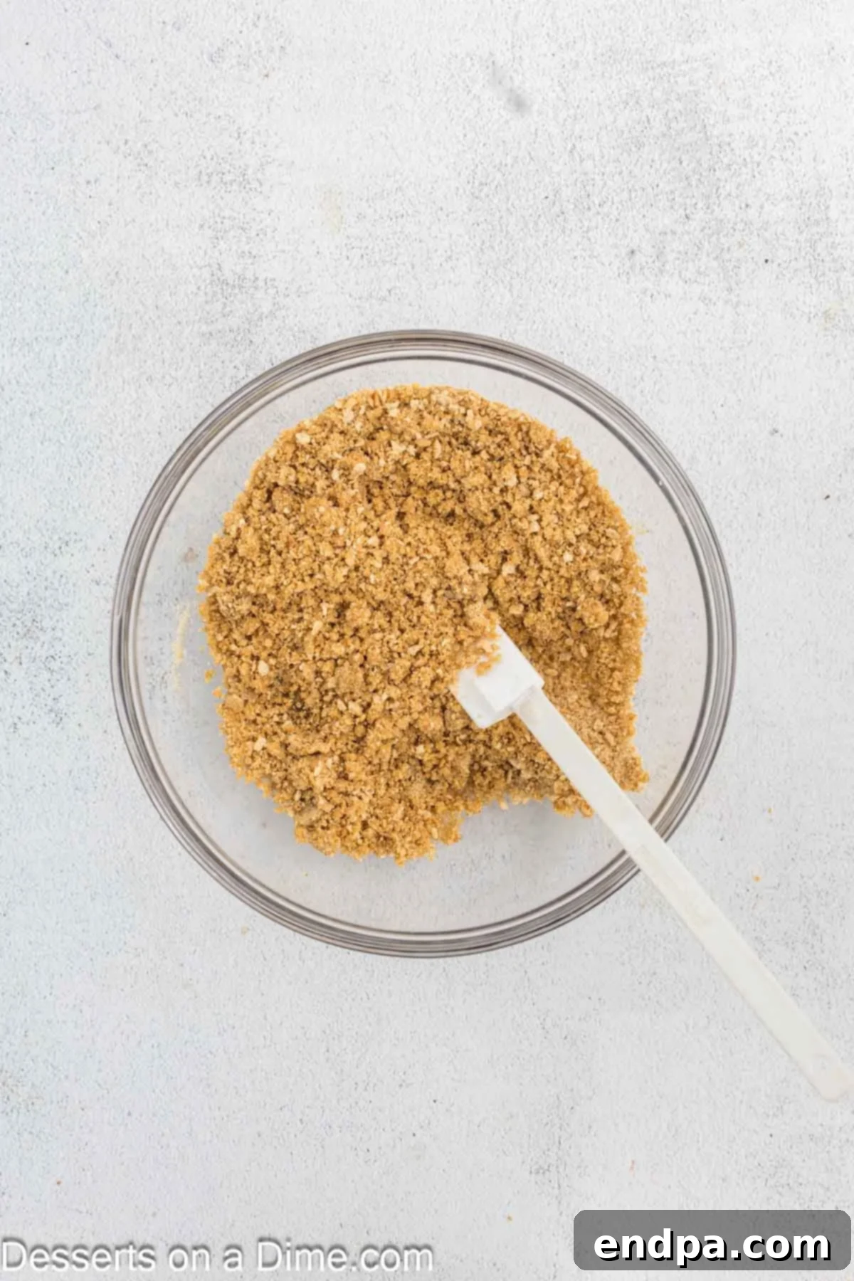 Crispy Caramel Cheesecake 4 Graham cracker crumbs in a bowl mixed with melted butter and brown sugar, ready for the cheesecake crust.