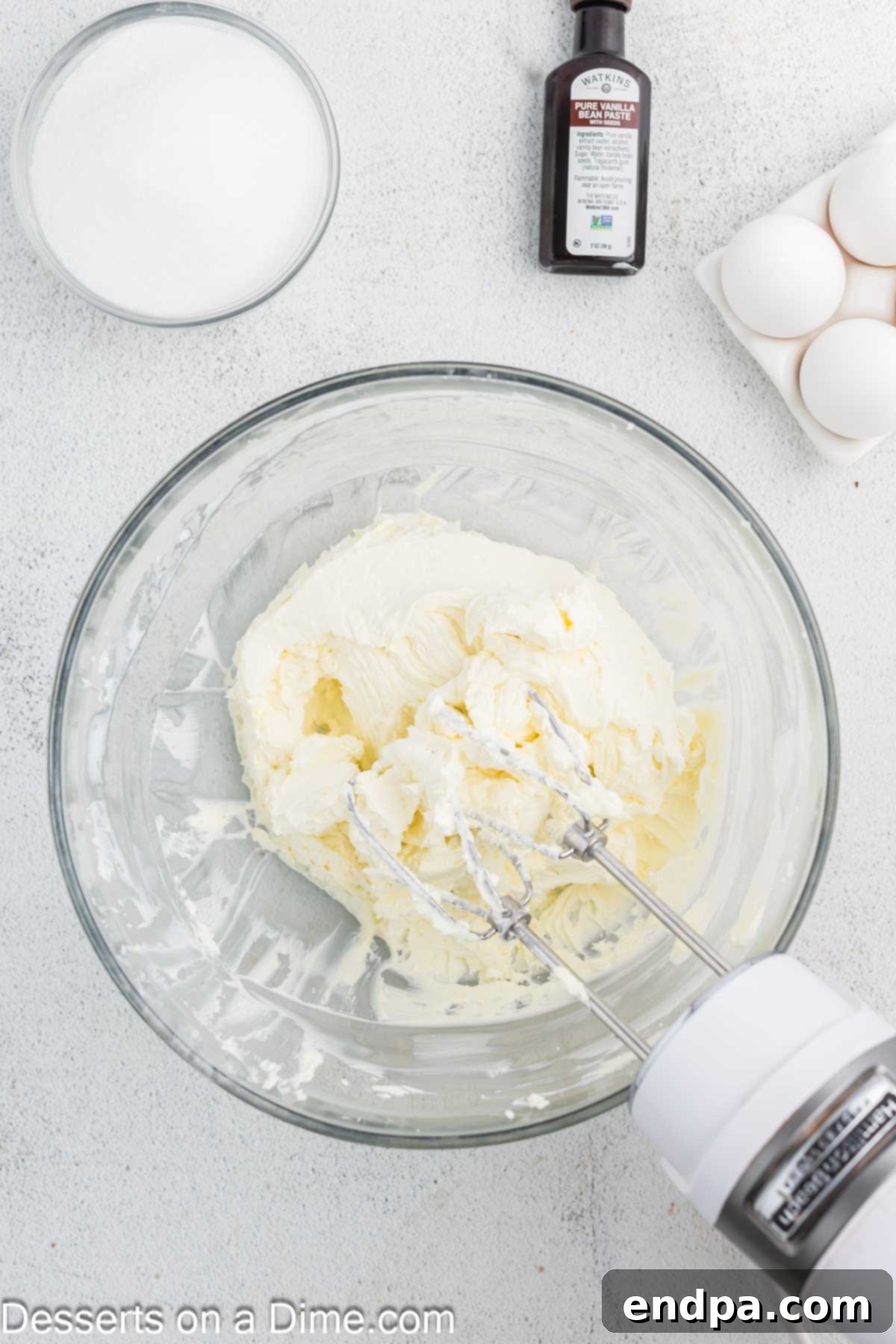Crispy Caramel Cheesecake 6 Softened cream cheese being beaten until light and fluffy in a large mixing bowl with an electric mixer.
