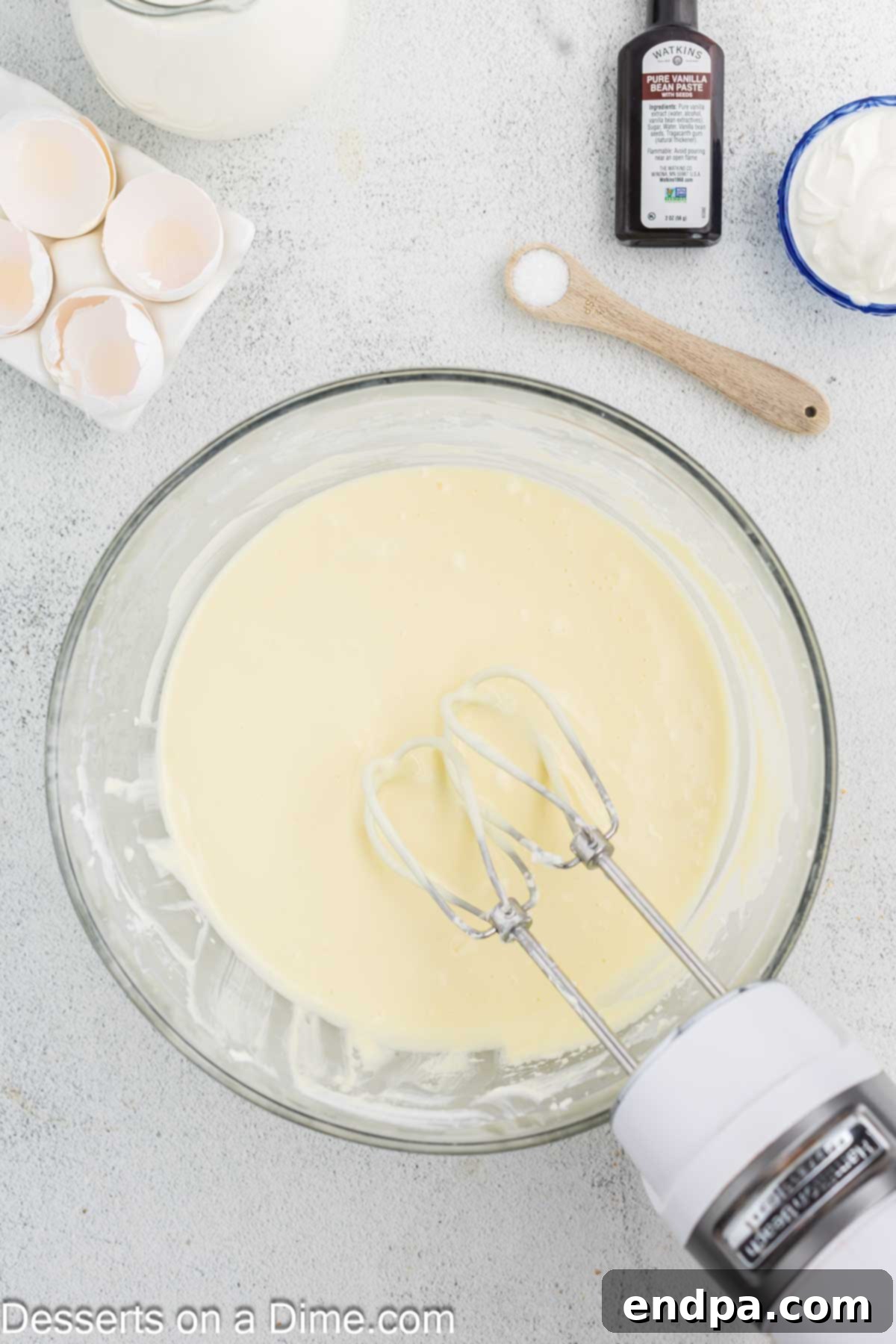 Crispy Caramel Cheesecake 7 Room temperature eggs being mixed into the cream cheese and sugar mixture, one at a time, until just combined.