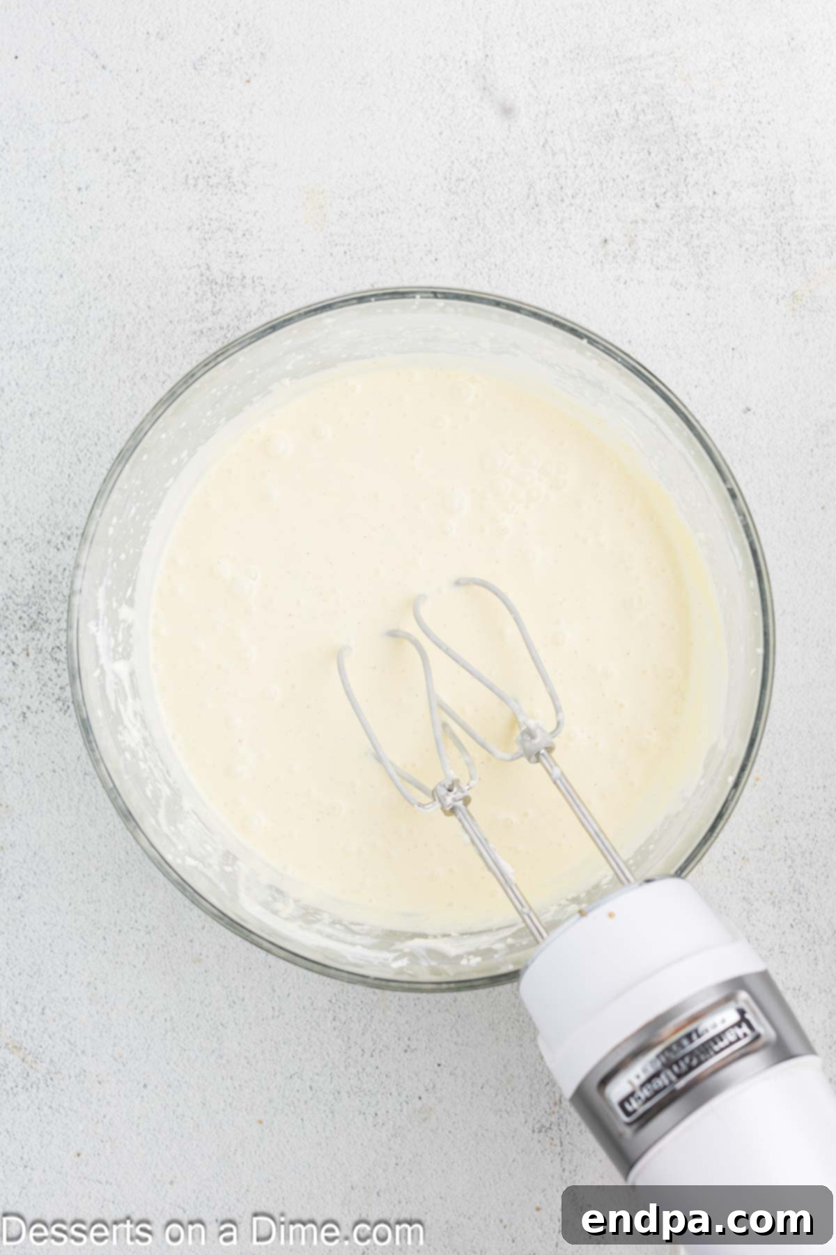 Crispy Caramel Cheesecake 8 Sour cream and cold heavy cream being gently mixed into the cheesecake batter on low speed.