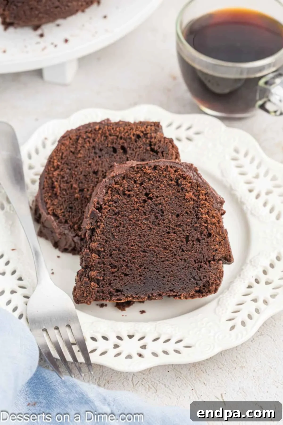 Velvet Chocolate Loaf 11 A slice of Chocolate Pound Cake is artfully placed on a plate, showcasing its moist texture and rich frosting, ready to be served.