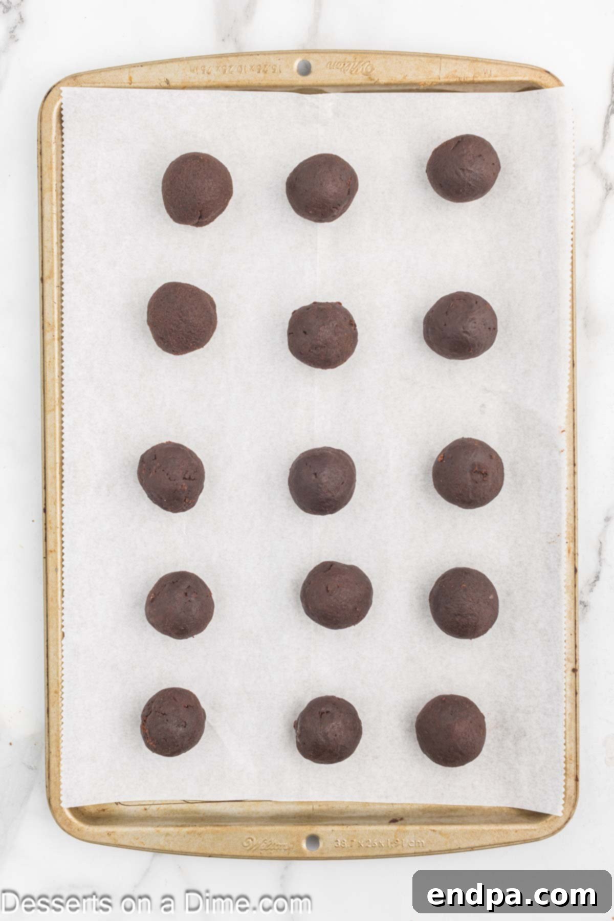Bite Sized Chocolate Bliss 10 Uniformly shaped chocolate cake balls placed on a parchment-lined baking sheet, ready for chilling.