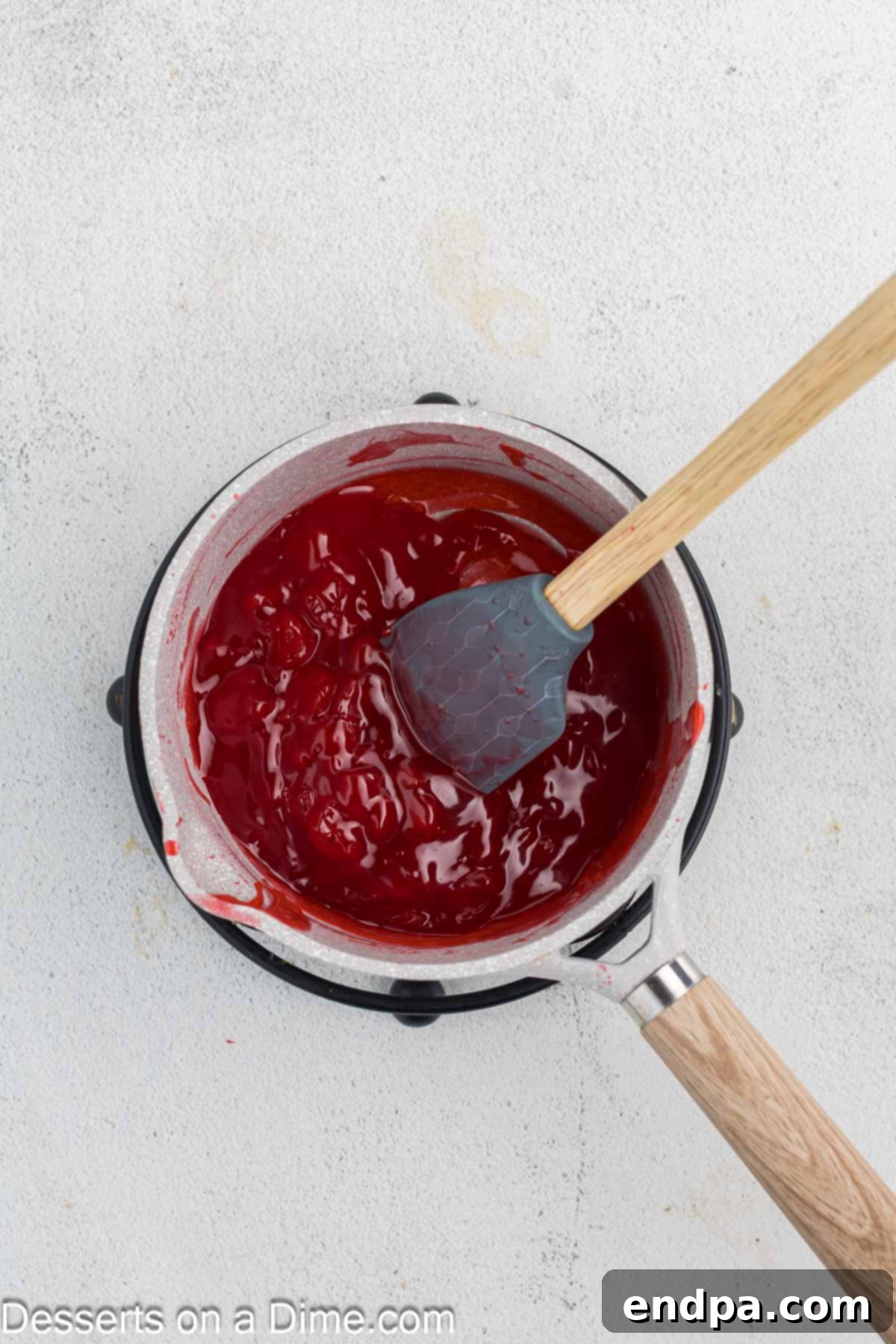 Cherry compote thickening in a pan after cornstarch has been added.