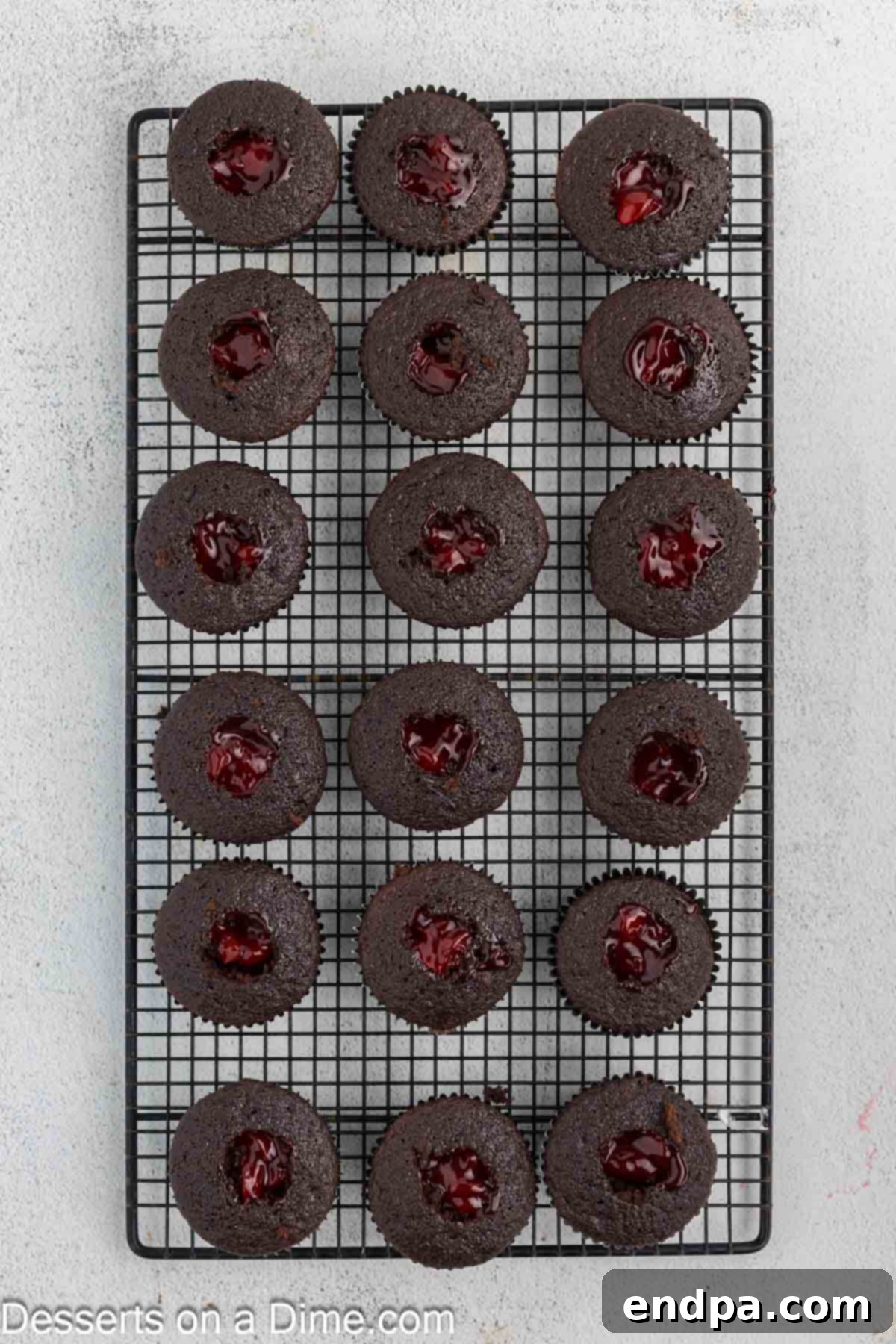 Cherry compote being spooned into the hollowed-out center of a cupcake.