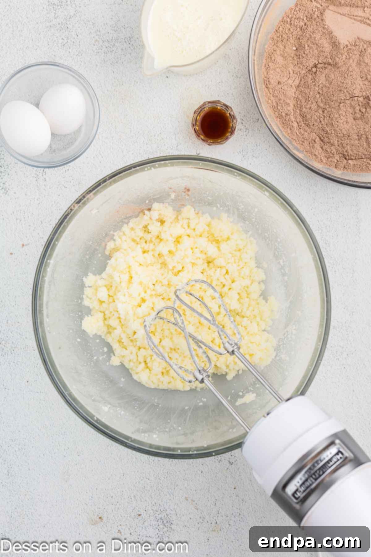 Softened butter and sugar being beaten until fluffy in a mixing bowl.