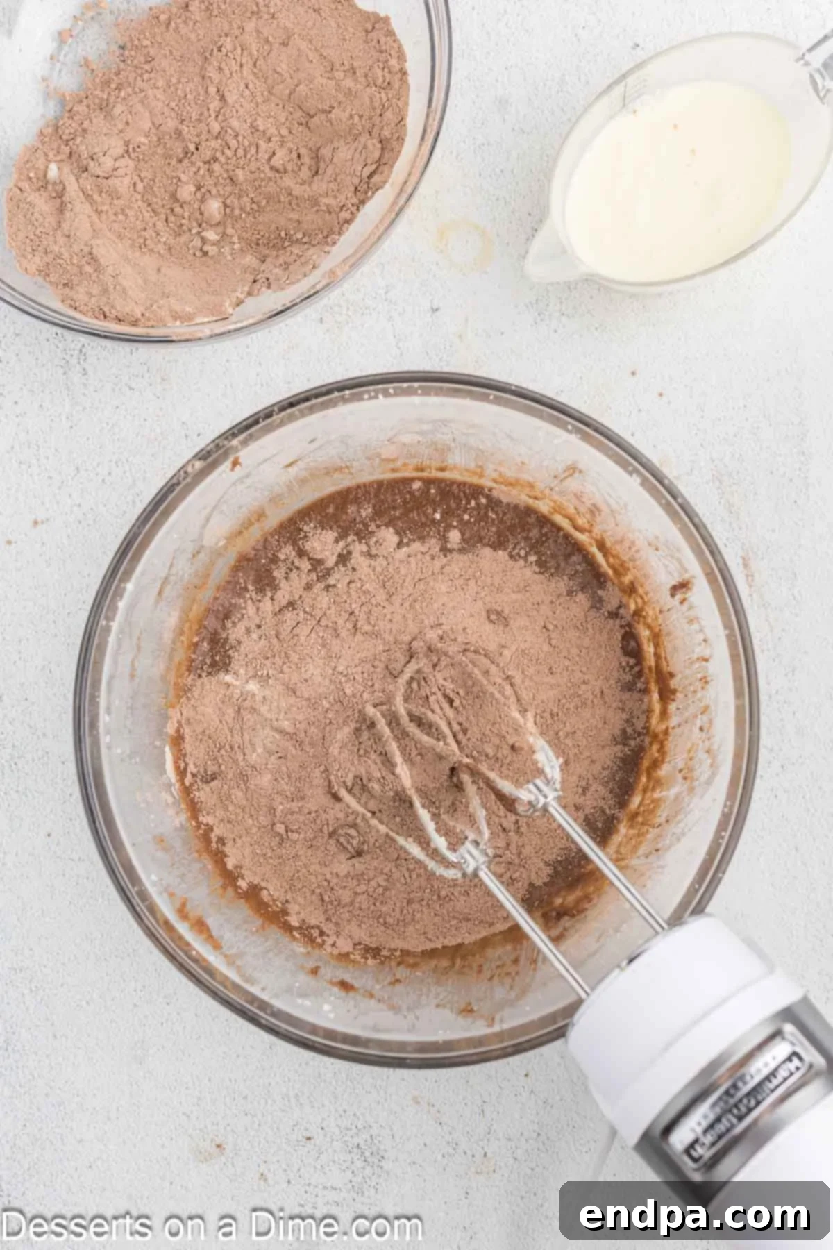 Dry ingredients gradually added to the wet ingredients in a mixing bowl.