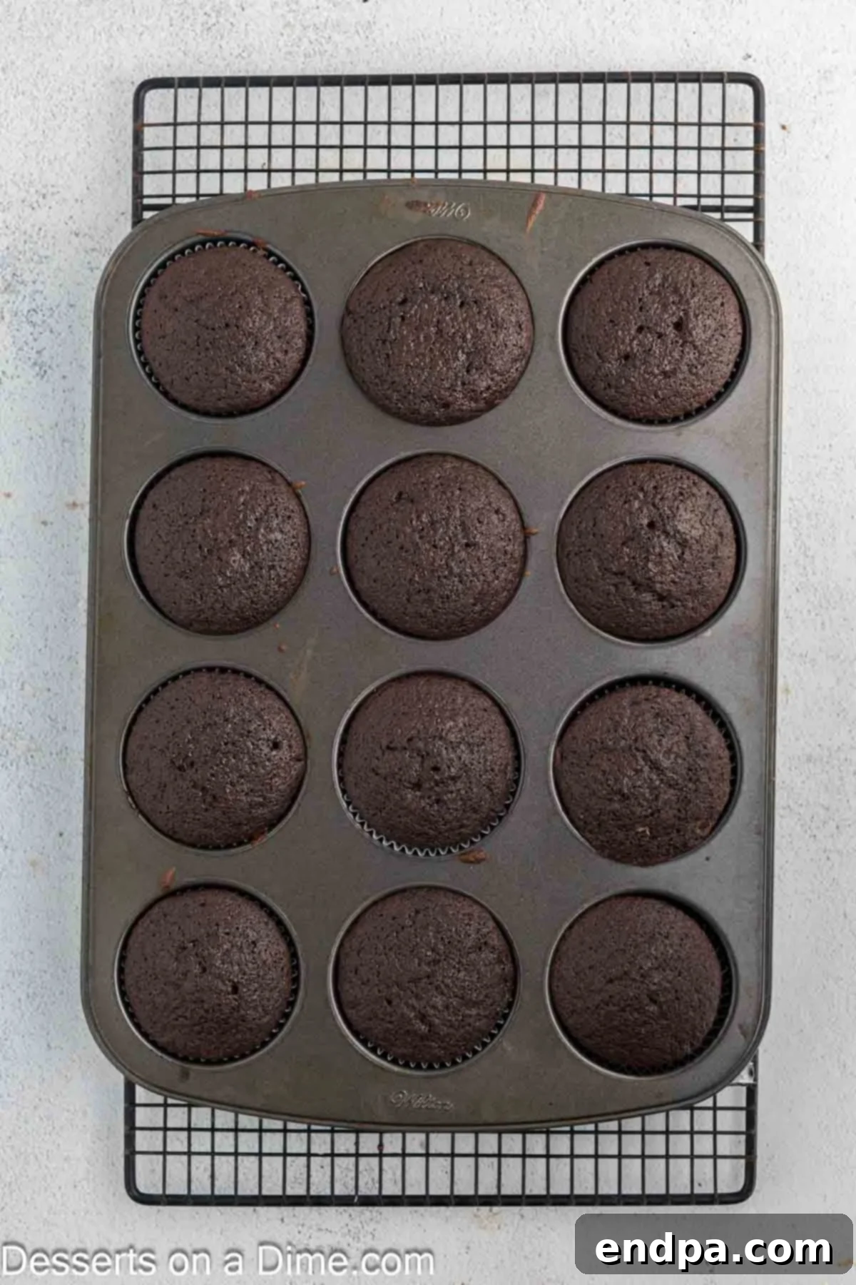 Baked cupcakes cooling on a wire rack after being removed from the oven.