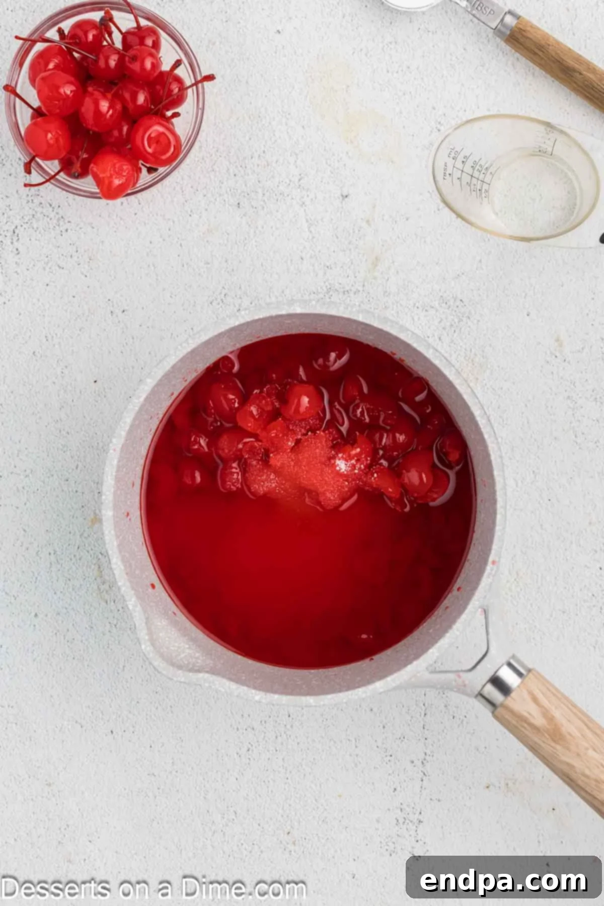 Maraschino cherries, their syrup, and sugar combined in a saucepan on the stovetop.