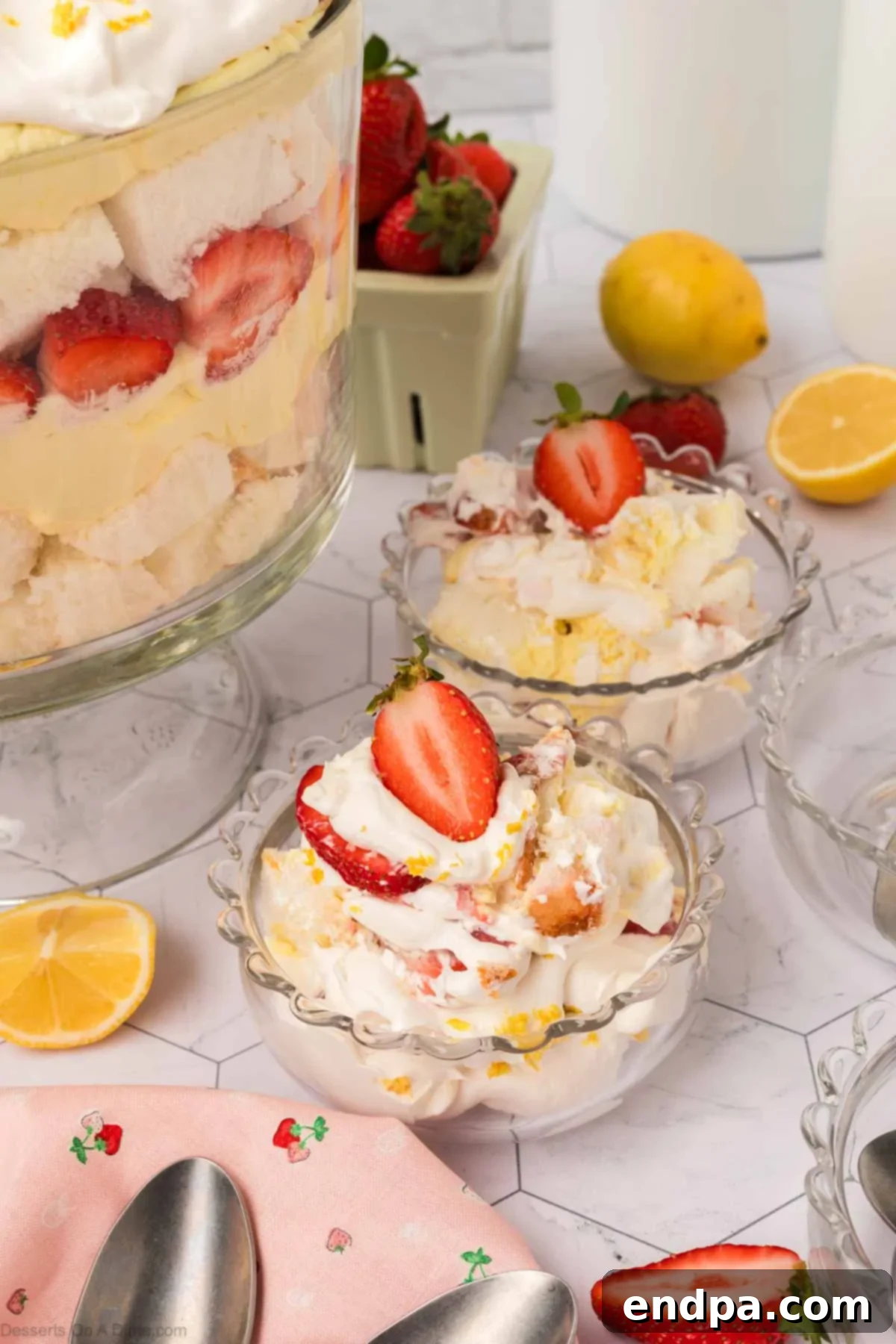 Individual servings of Lemon Strawberry Trifle in small clear bowls, garnished with fresh strawberries.