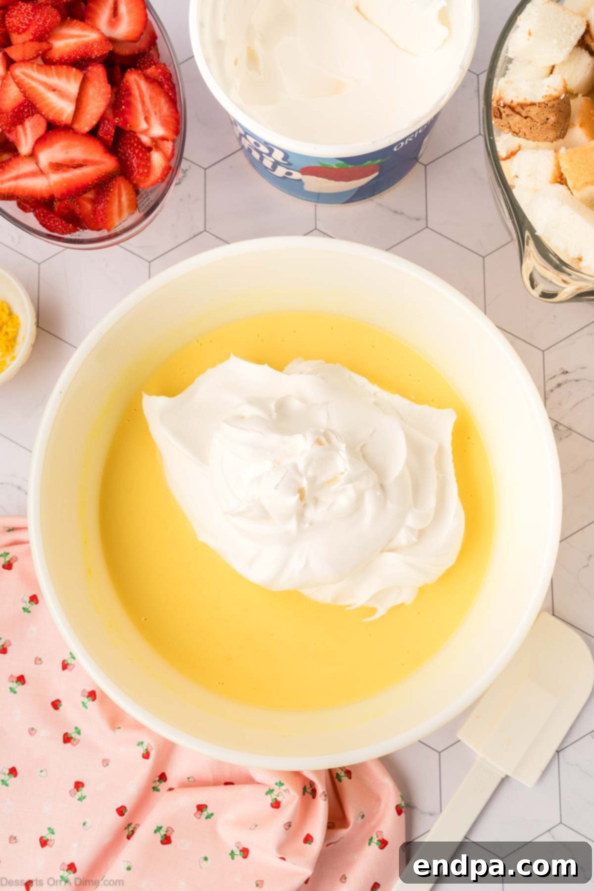 Half of the whipped topping is gently folded into the lemon pudding mixture.