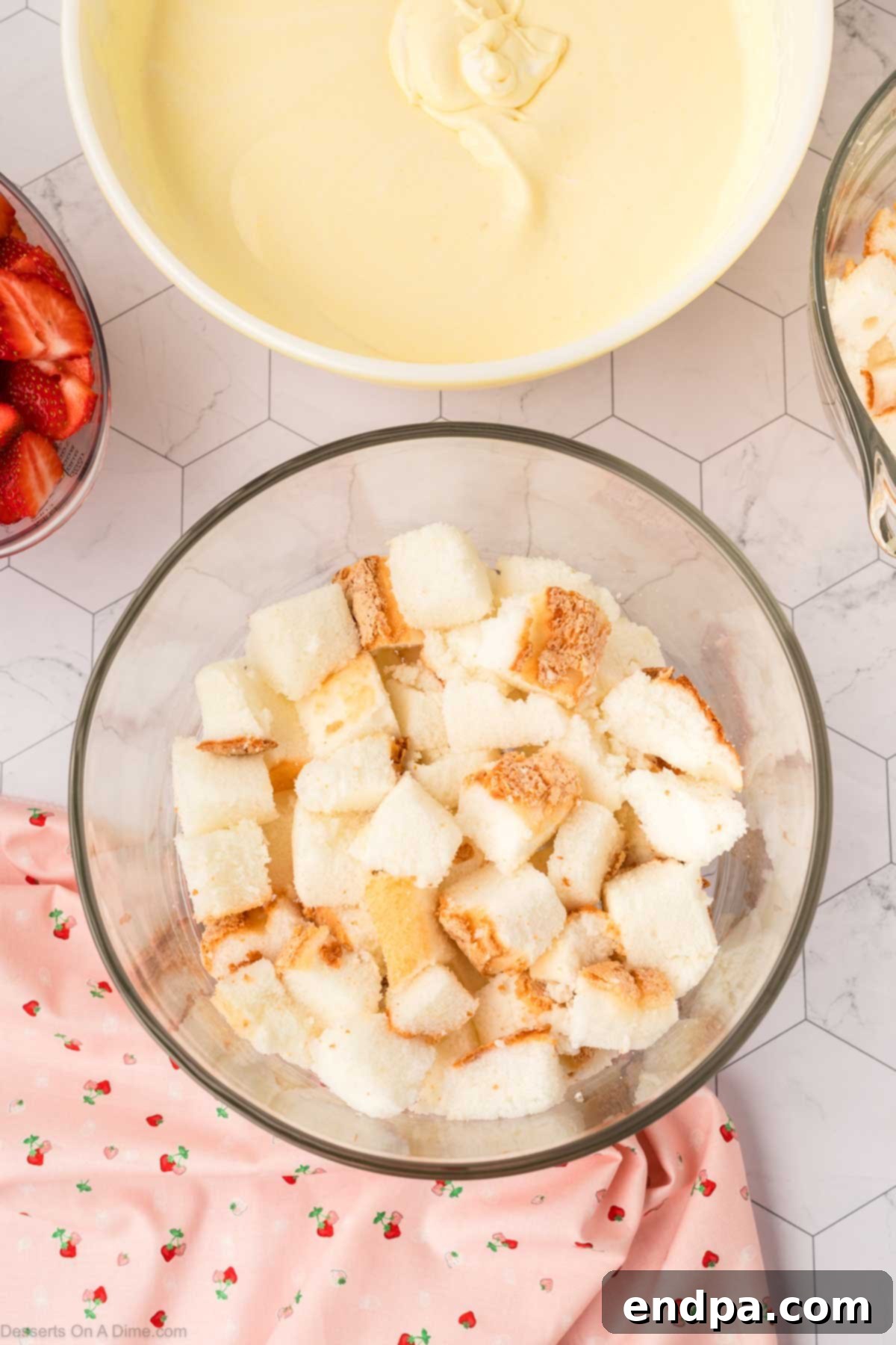 First layer of cubed angel food cake at the bottom of a clear trifle dish.
