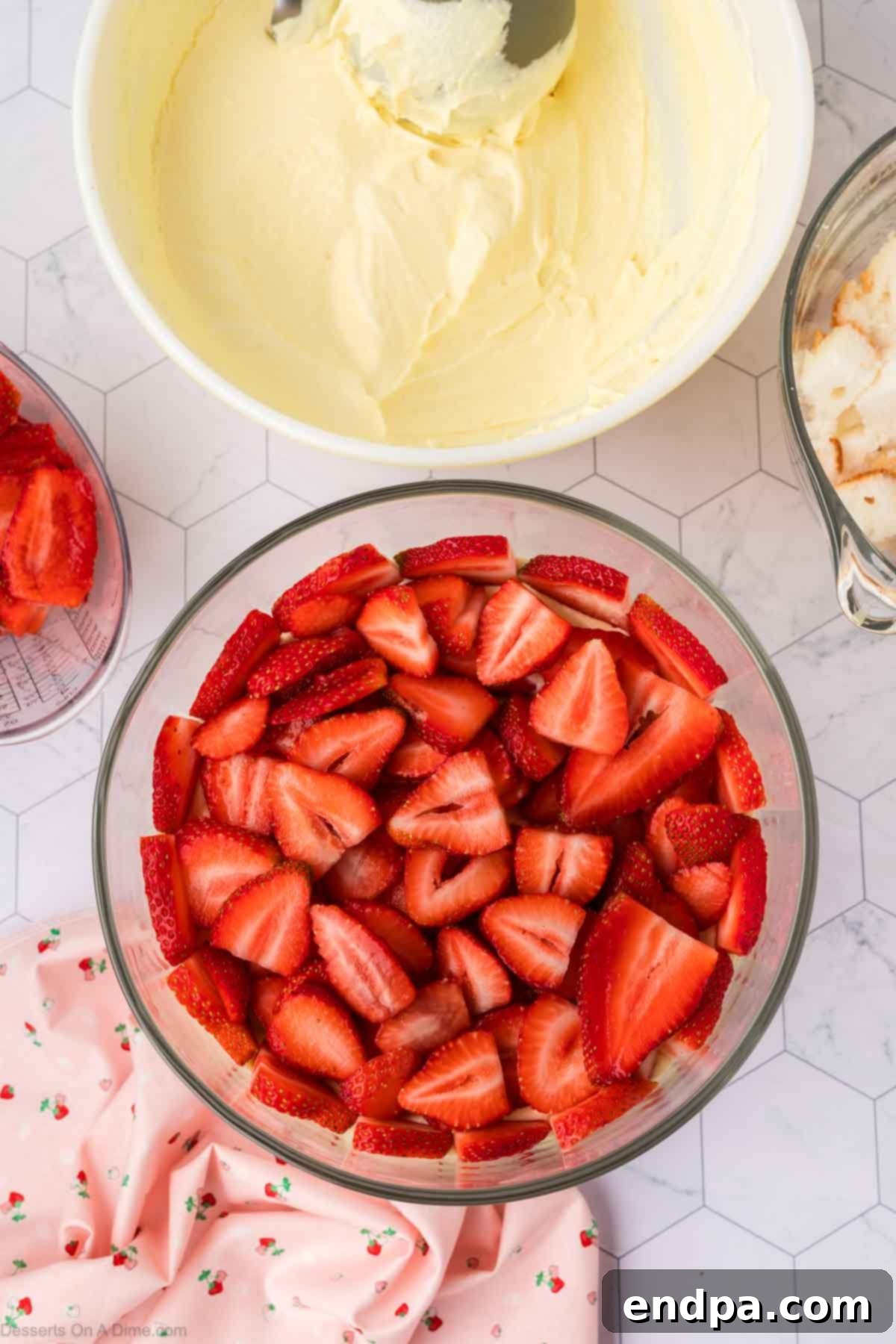 Sliced strawberries layered over cake in a trifle dish.