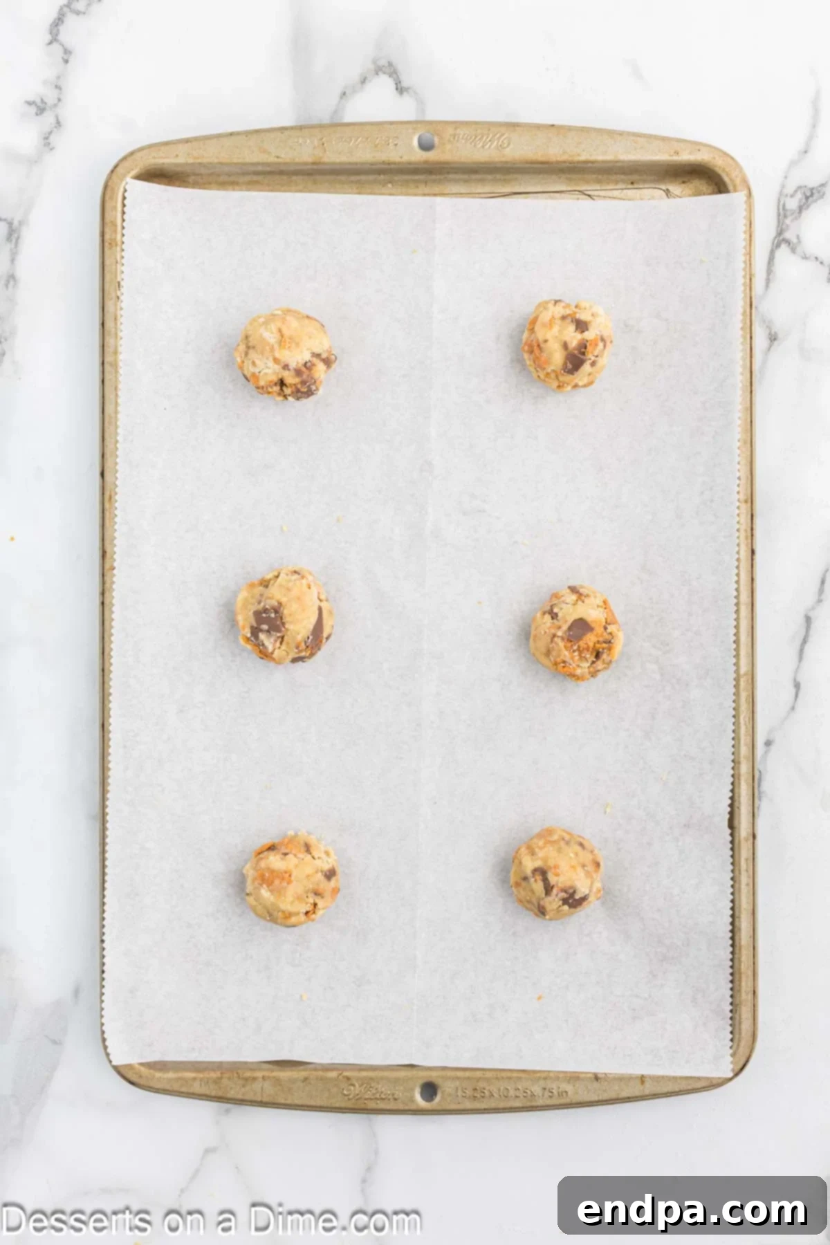Butterfinger cookie dough balls on lined baking sheet.