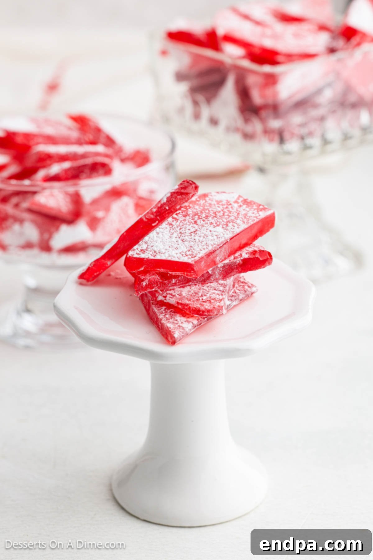 Red hard candy piled on a pedestal for serving, perfectly capturing its glossy texture.
