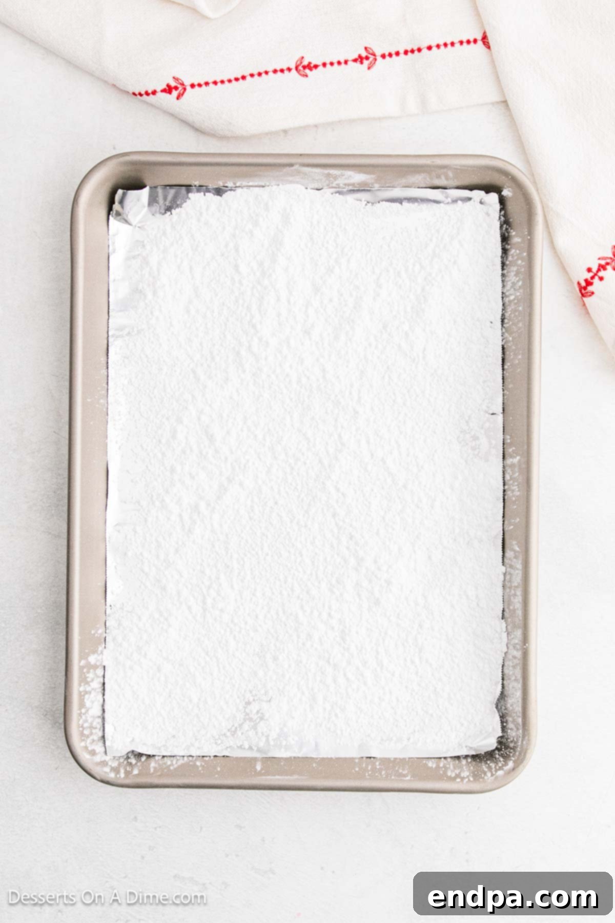 Powdered sugar generously sprinkled on a lined baking sheet, ready for the hot candy mixture.