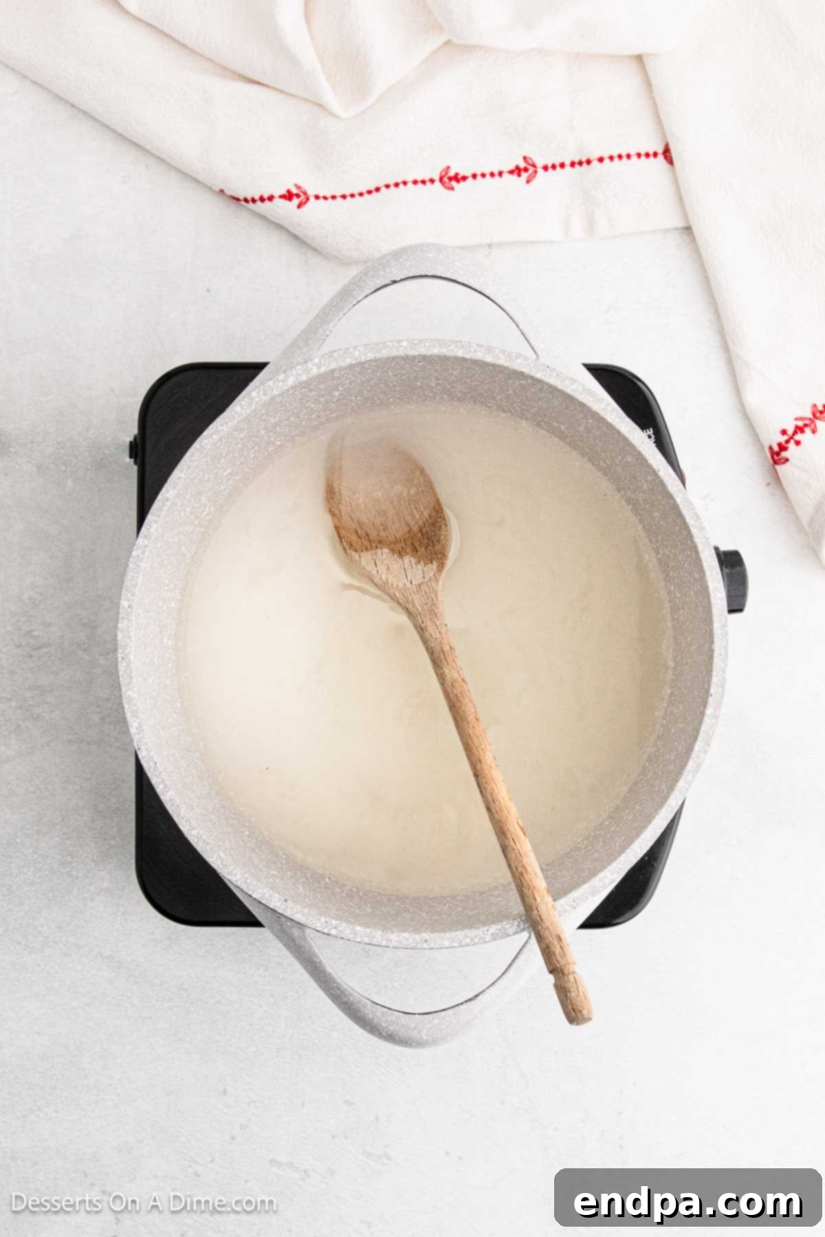 Granulated sugar, water, and corn syrup mixture simmering in a pan over medium heat.