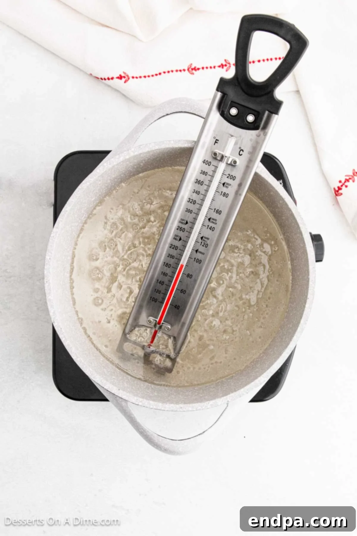 A candy thermometer carefully placed in the boiling sugar mixture, displaying the temperature.