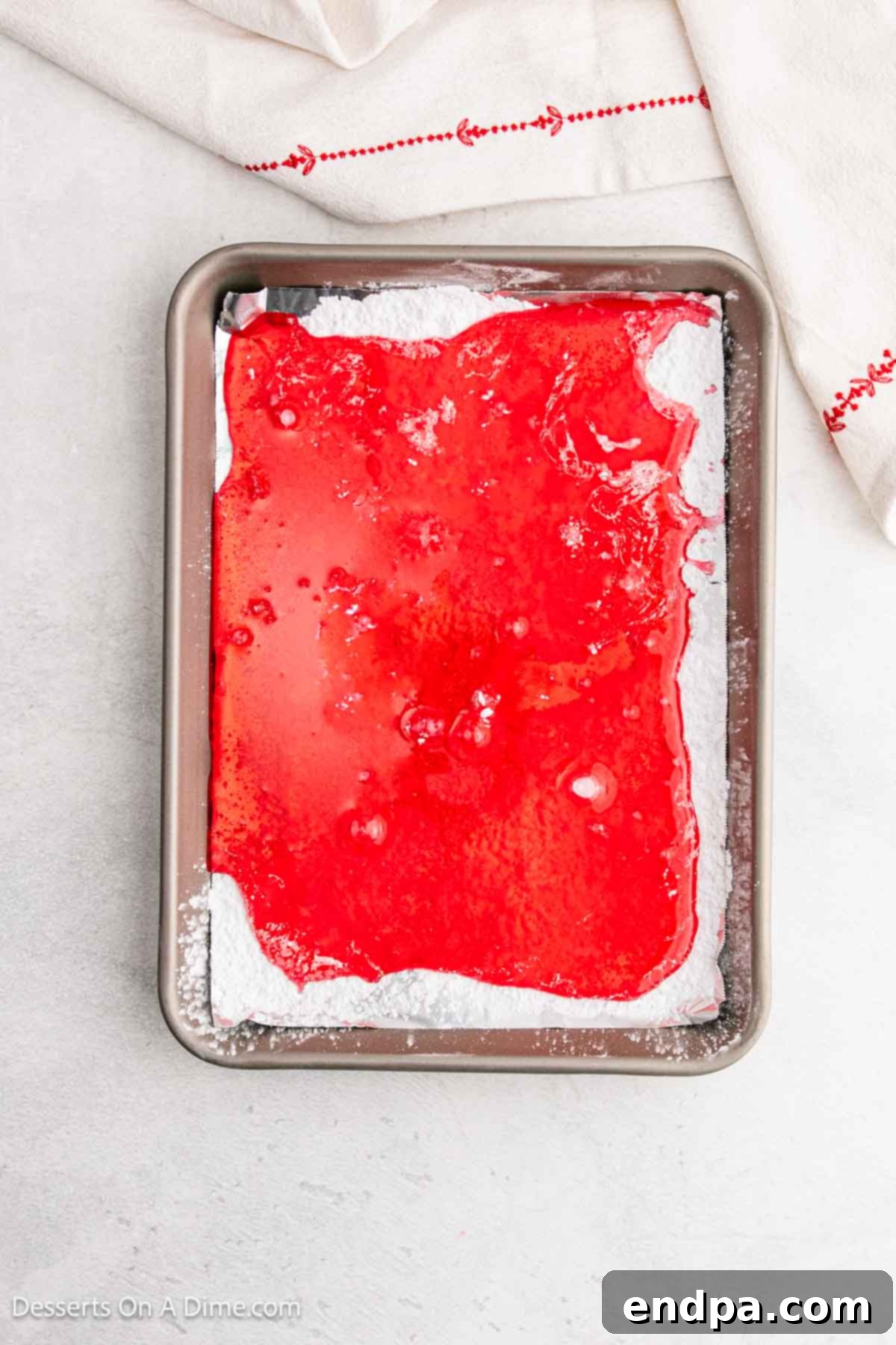 Hot candy mixture being carefully poured onto the prepared baking sheet, spreading evenly.