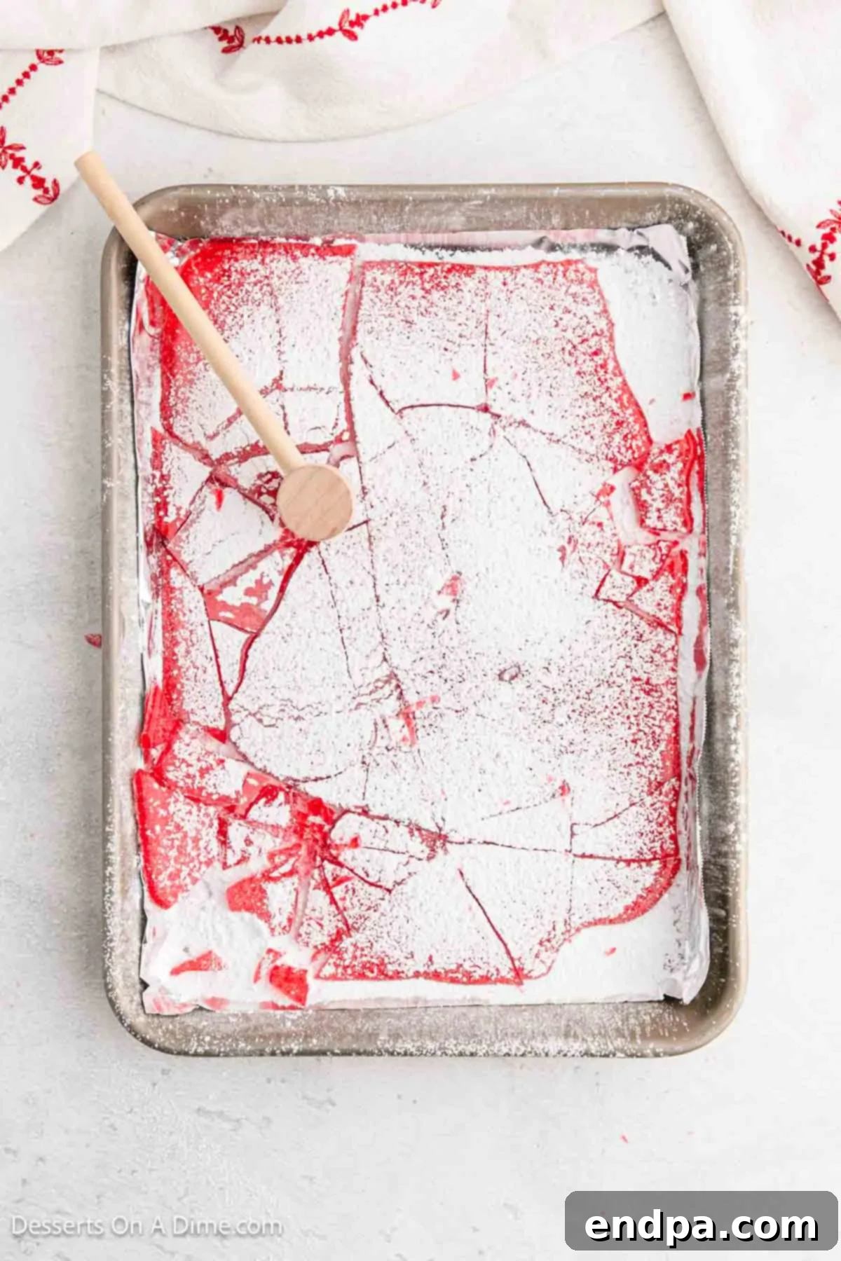 A mallet breaking the hardened sheet of candy into small, irregular pieces.