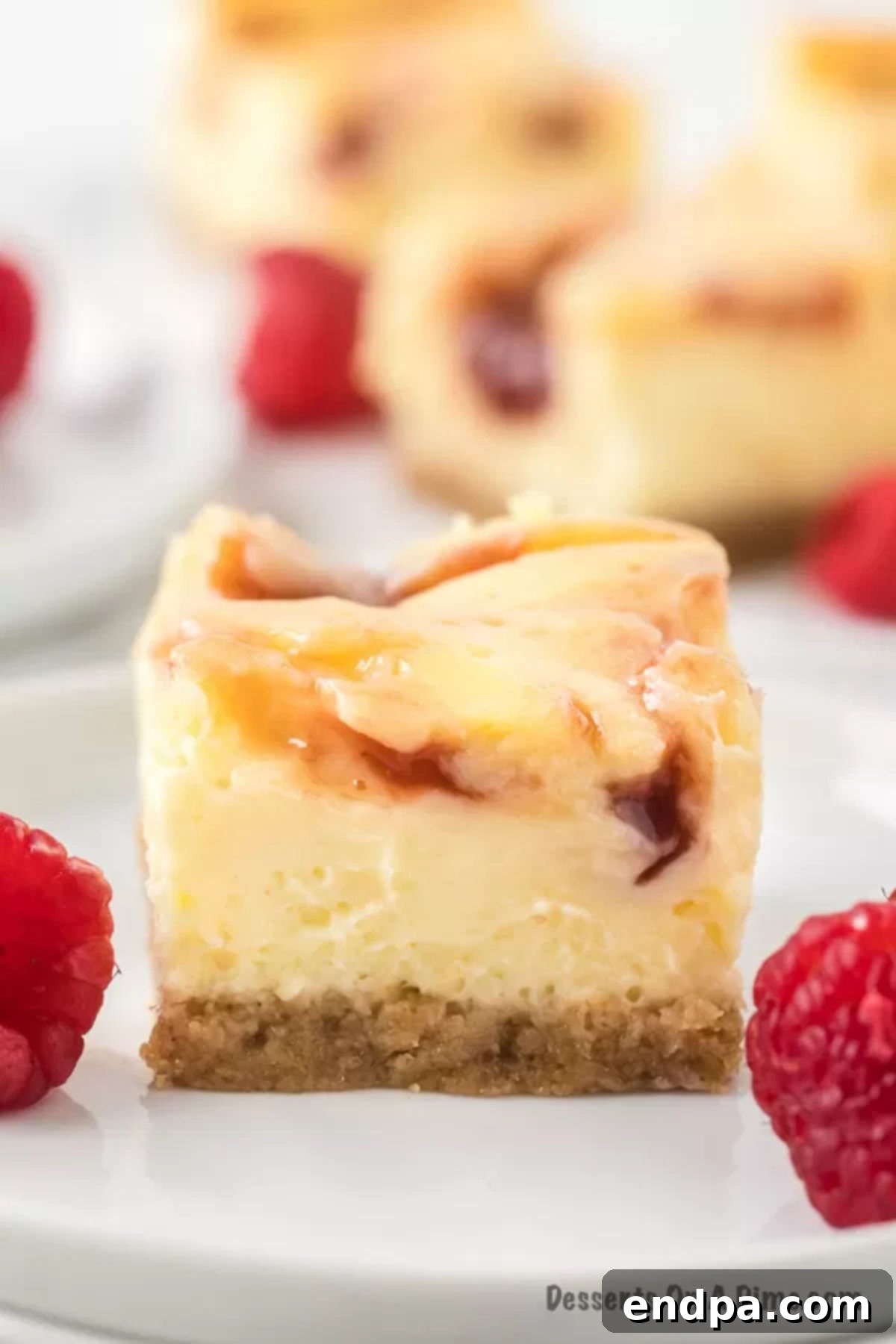 Decadent Raspberry Cheesecake Bars 2 Slice of raspberry cheesecake bars on a plate.