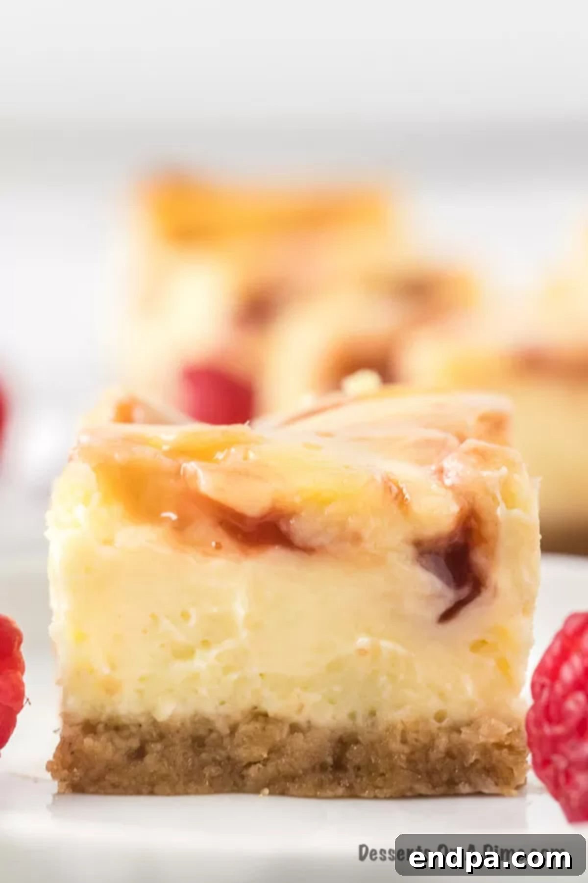 Decadent Raspberry Cheesecake Bars 12 Slice of raspberry bars on plate.