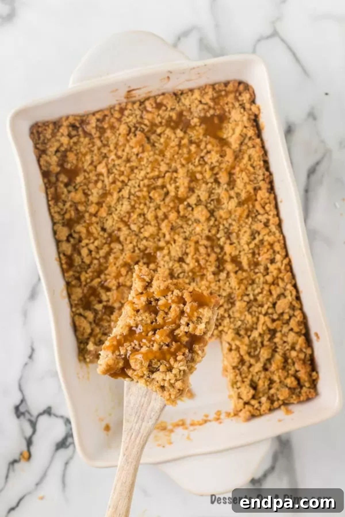Several neatly cut Caramel Apple Cheesecake Bars arranged on a serving plate, each showing distinct layers of crust, cheesecake, apples, and streusel, with caramel drizzle.