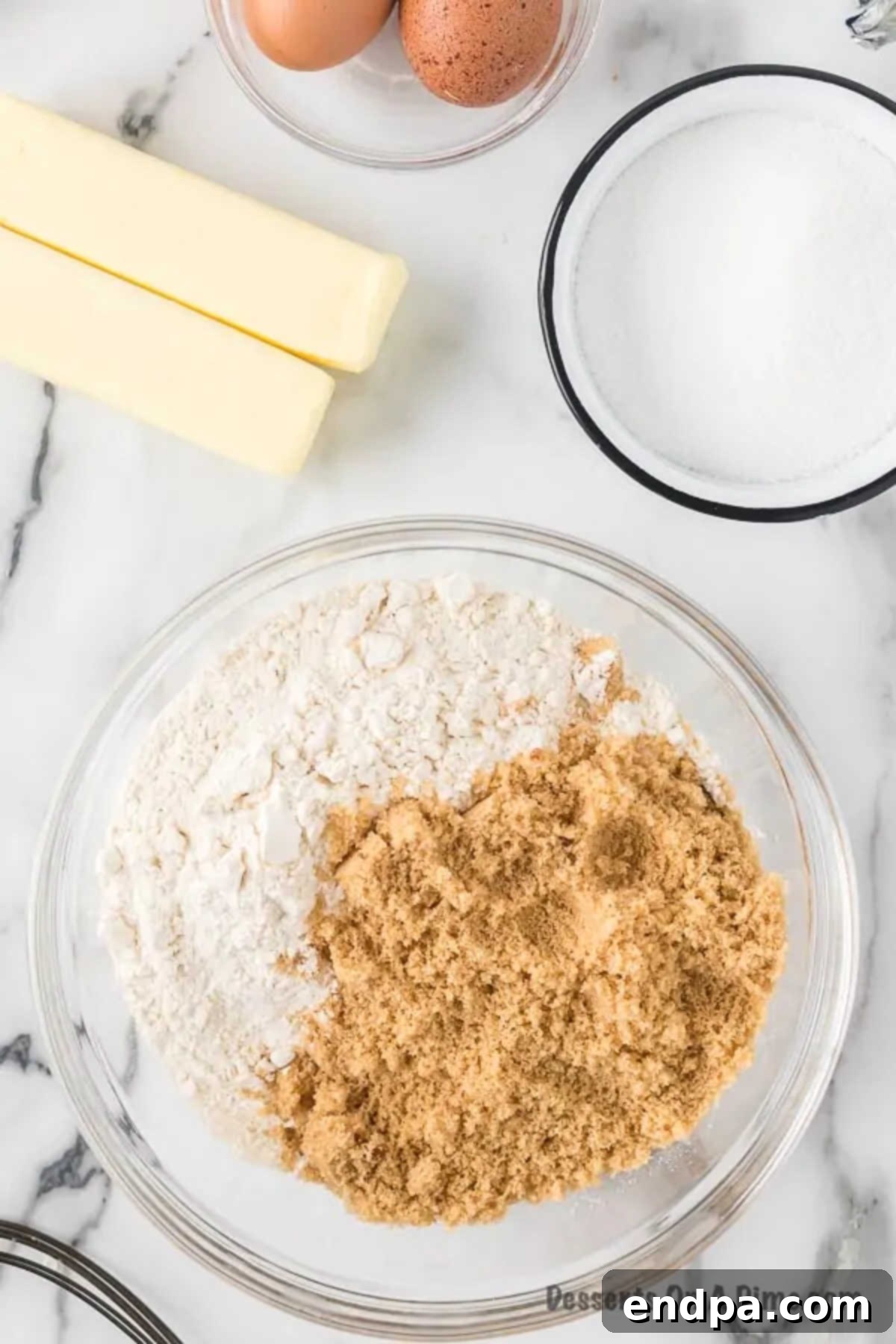 Mixing bowl with all-purpose flour and packed brown sugar combined, ready for butter.