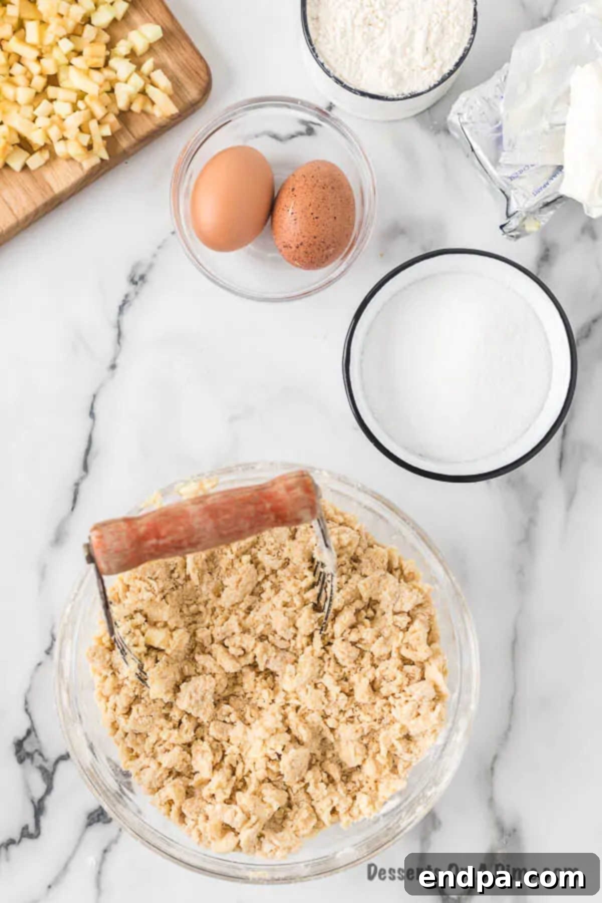 Softened butter cubes being cut into the flour and brown sugar mixture using a pastry blender.