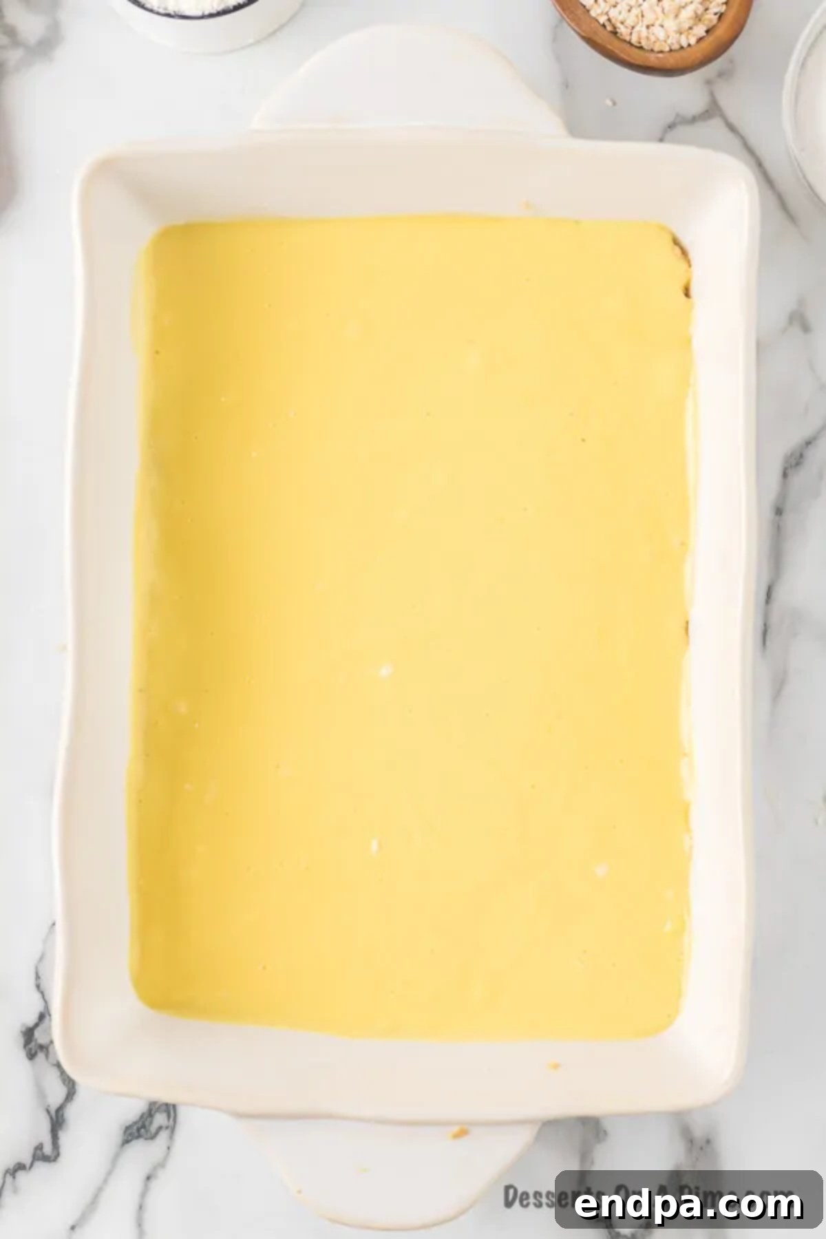 The creamy cheesecake batter evenly spread over the partially baked shortbread crust in the baking dish.