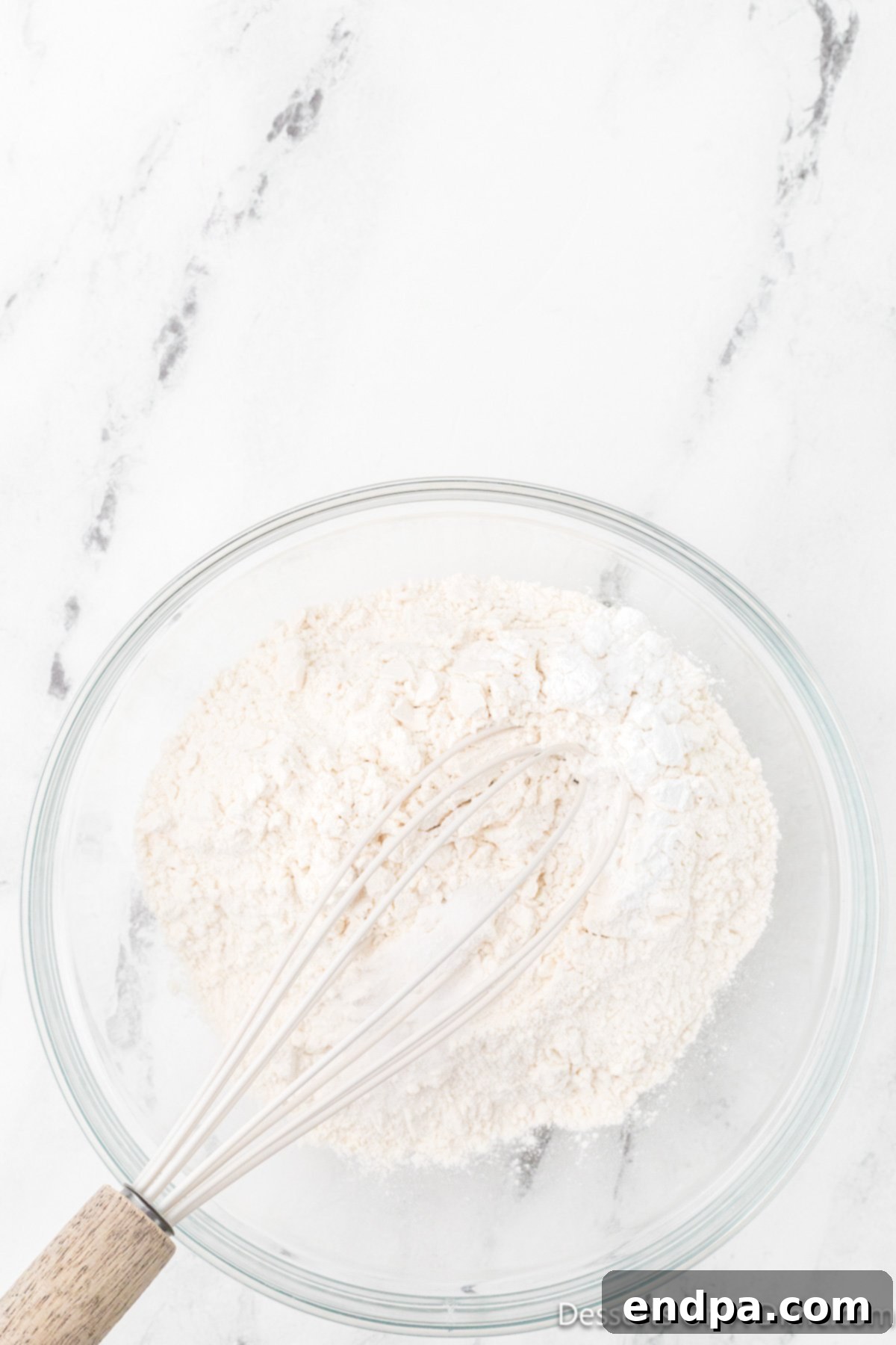 Flour, baking powder, and salt are carefully combined in a large mixing bowl, ready for the wet ingredients.