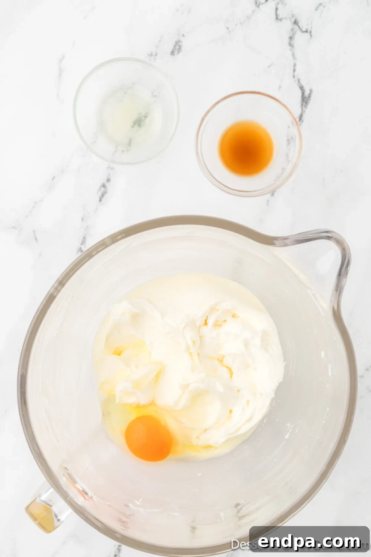 Granulated sugar, a large egg, vanilla extract, and pineapple juice are added to the creamed butter and cream cheese mixture.