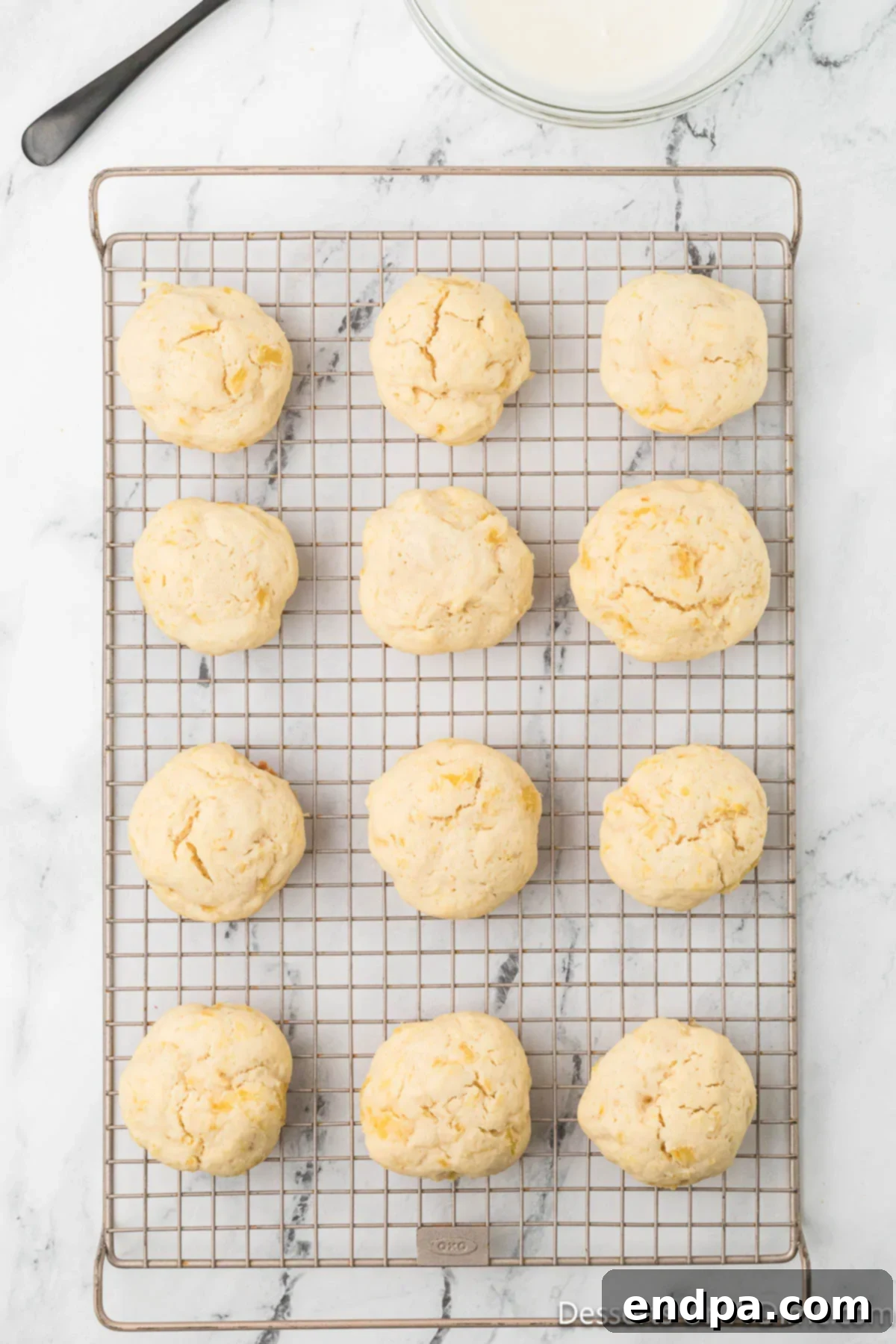 Baked pineapple cookies transferred to a wire rack to cool completely, ensuring they are ready for glazing.