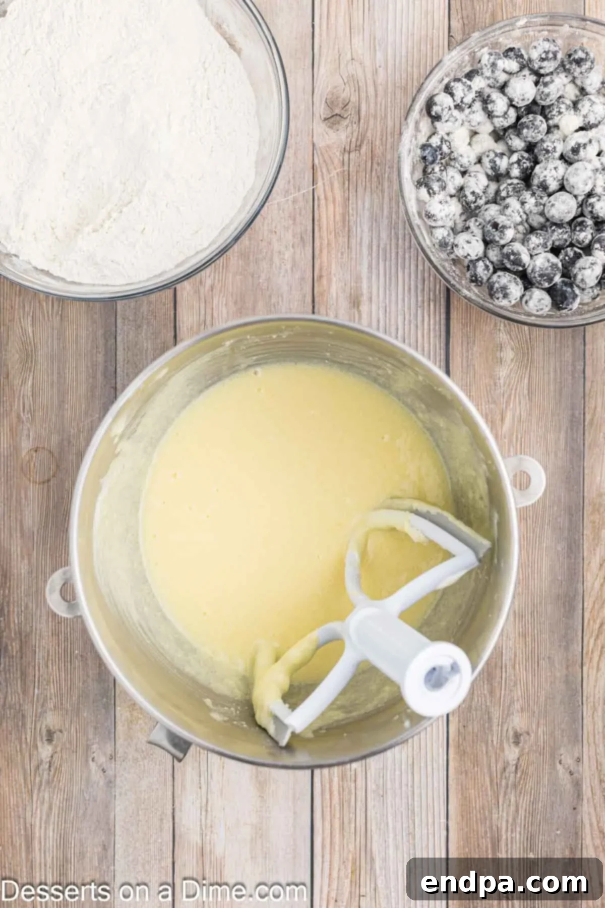 Sapphire Swirl Cake 5 Eggs and sour cream being added to the creamed butter and sugar mixture.